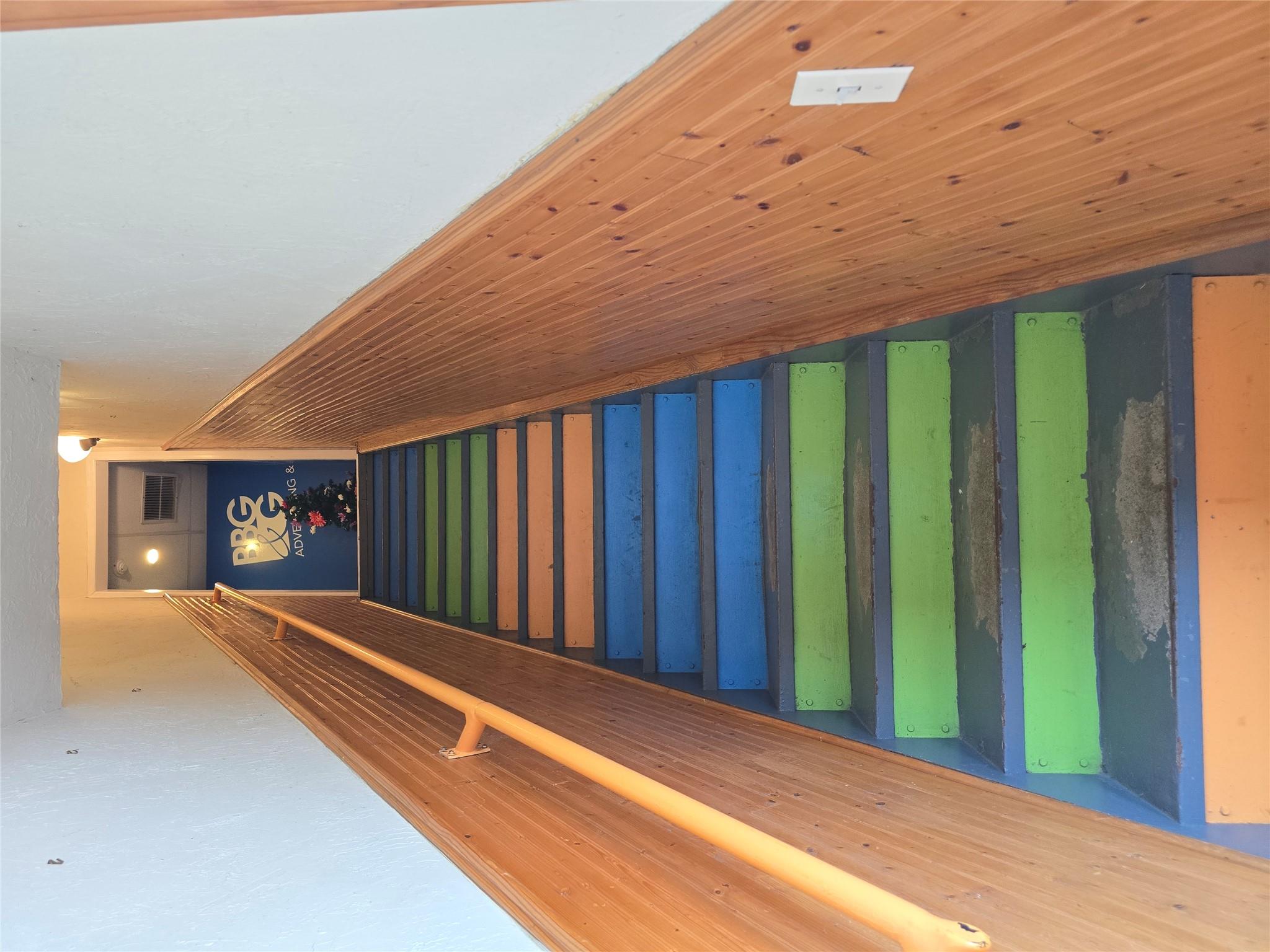 Staircase featuring wainscoting and wood walls