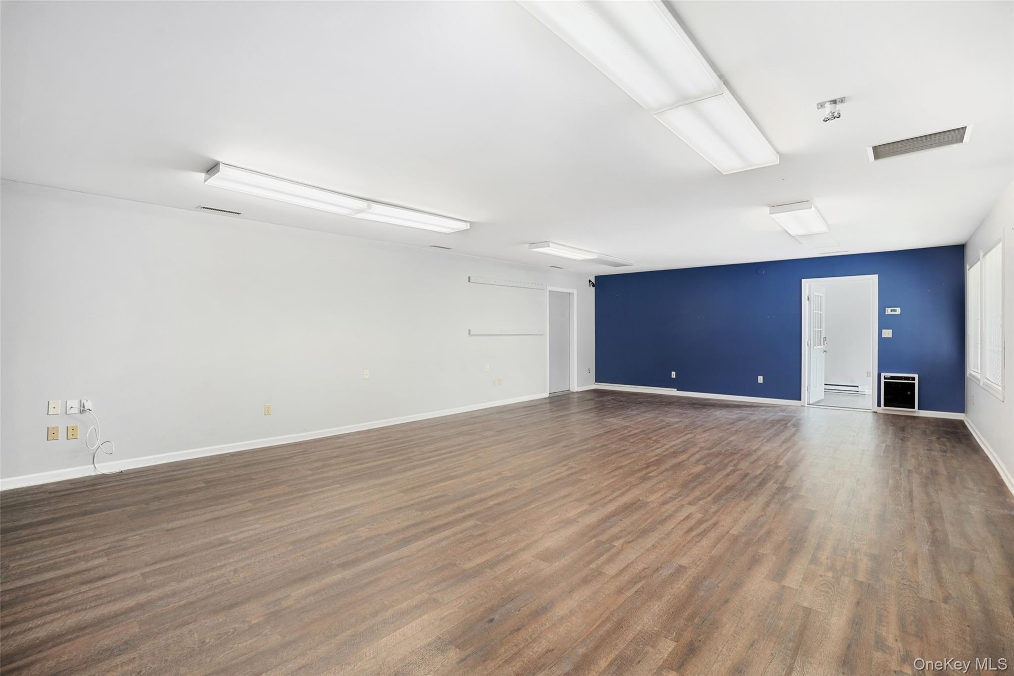 Unfurnished room with dark wood-style flooring and baseboards