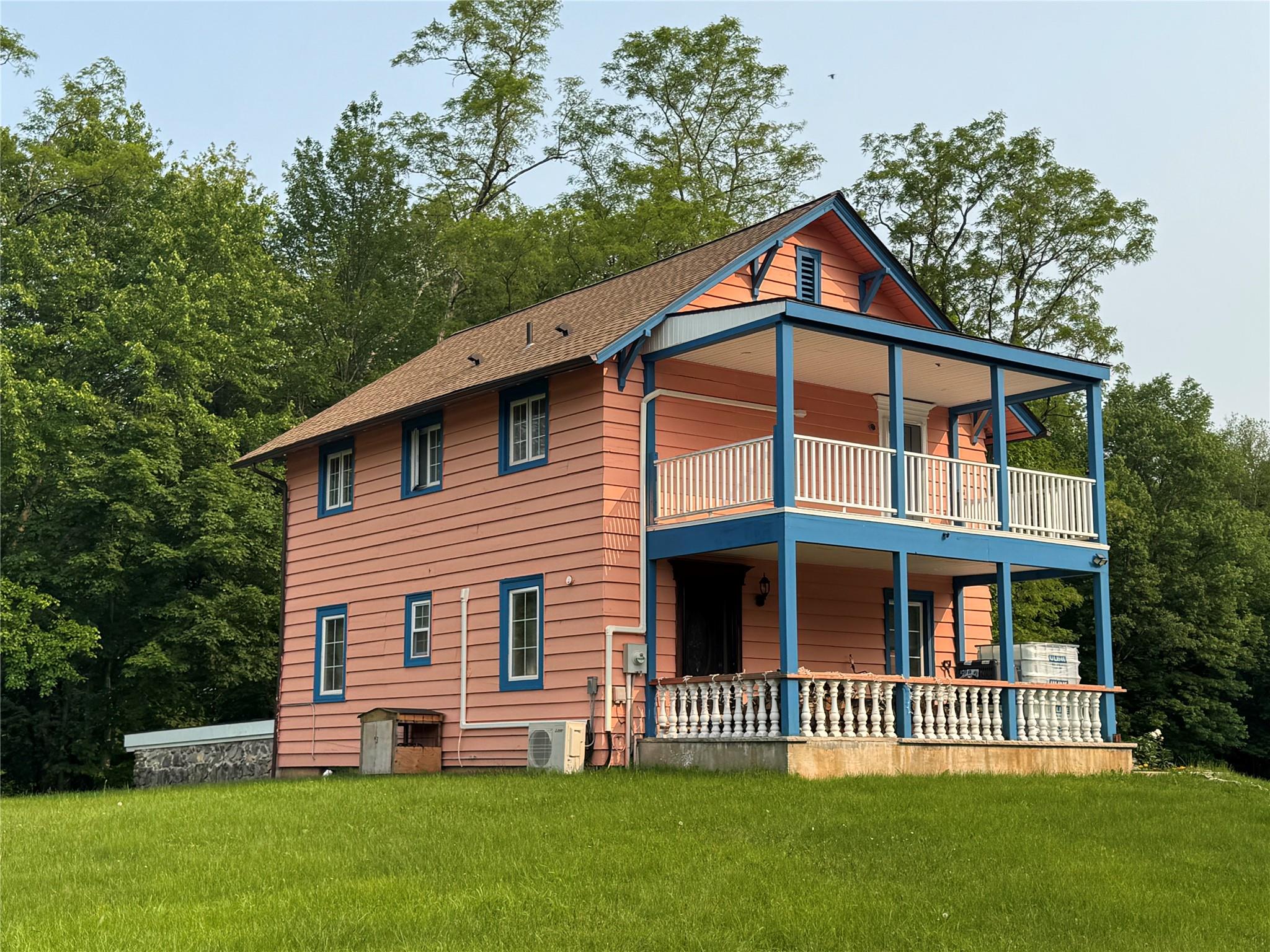 Back of property with a balcony, a yard, and a shingled roof