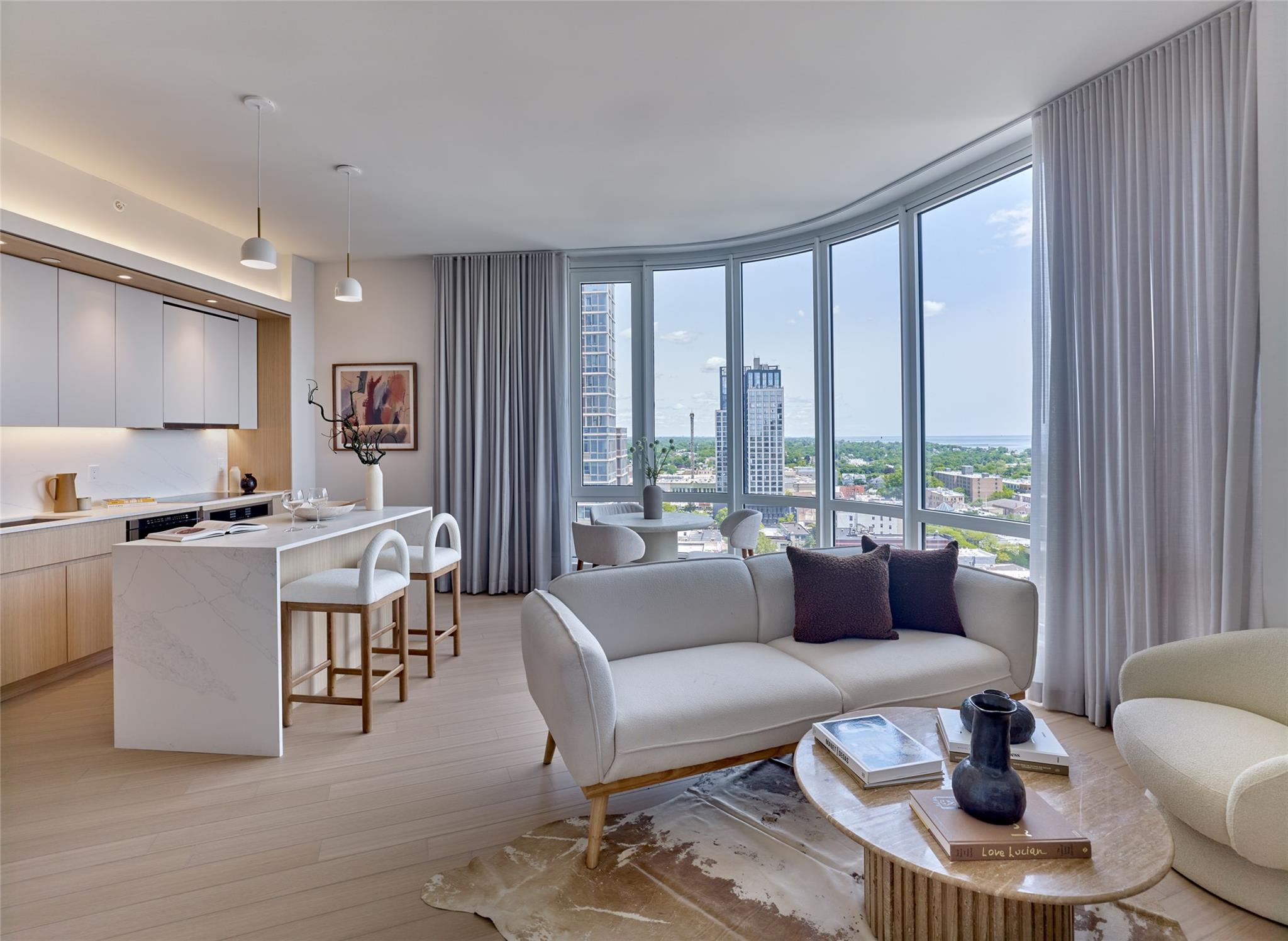 Living area featuring plenty of natural light, light wood-type flooring, a view of city, and expansive windows
