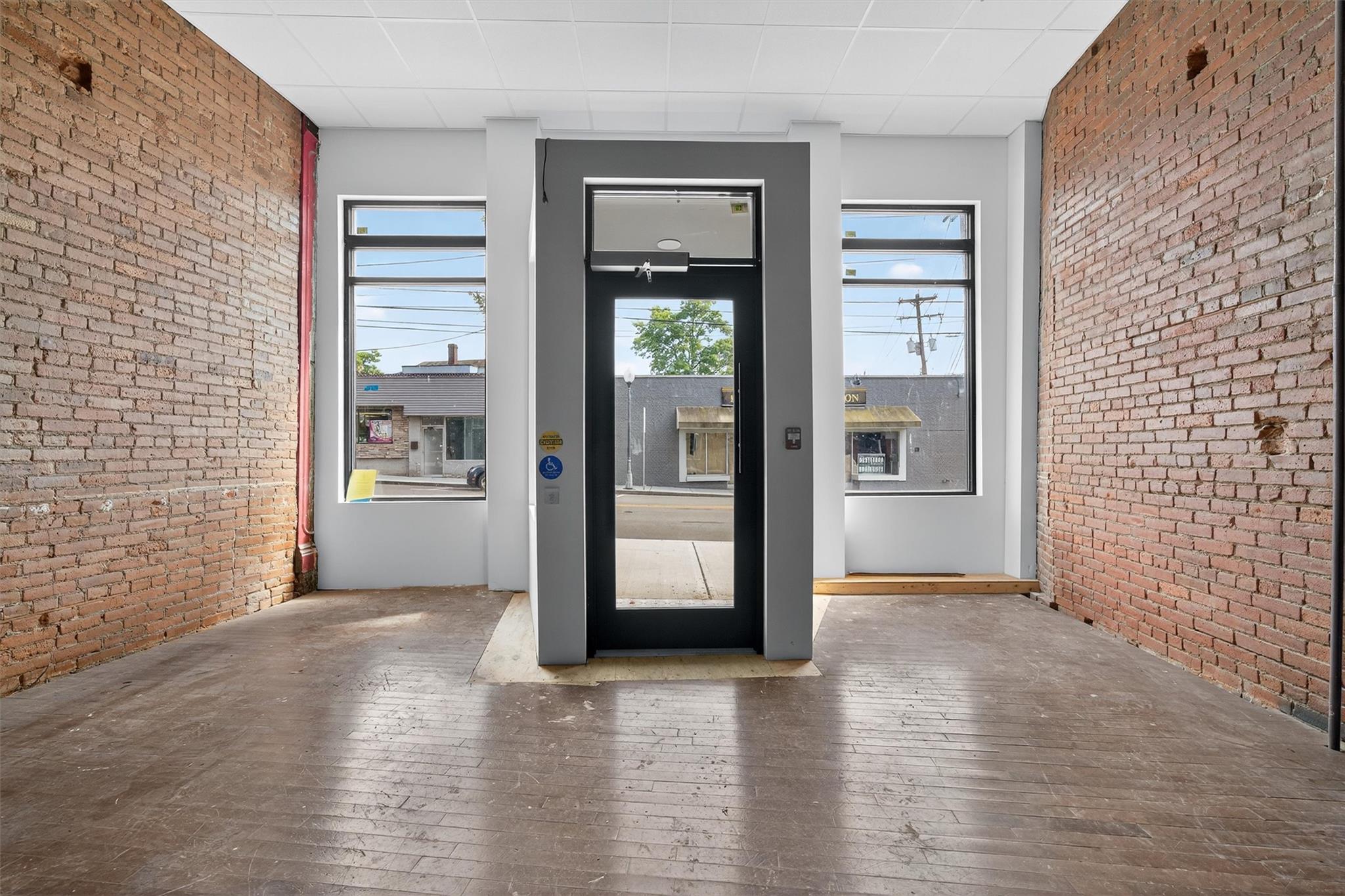 Entrance foyer featuring brick wall and wood-type flooring