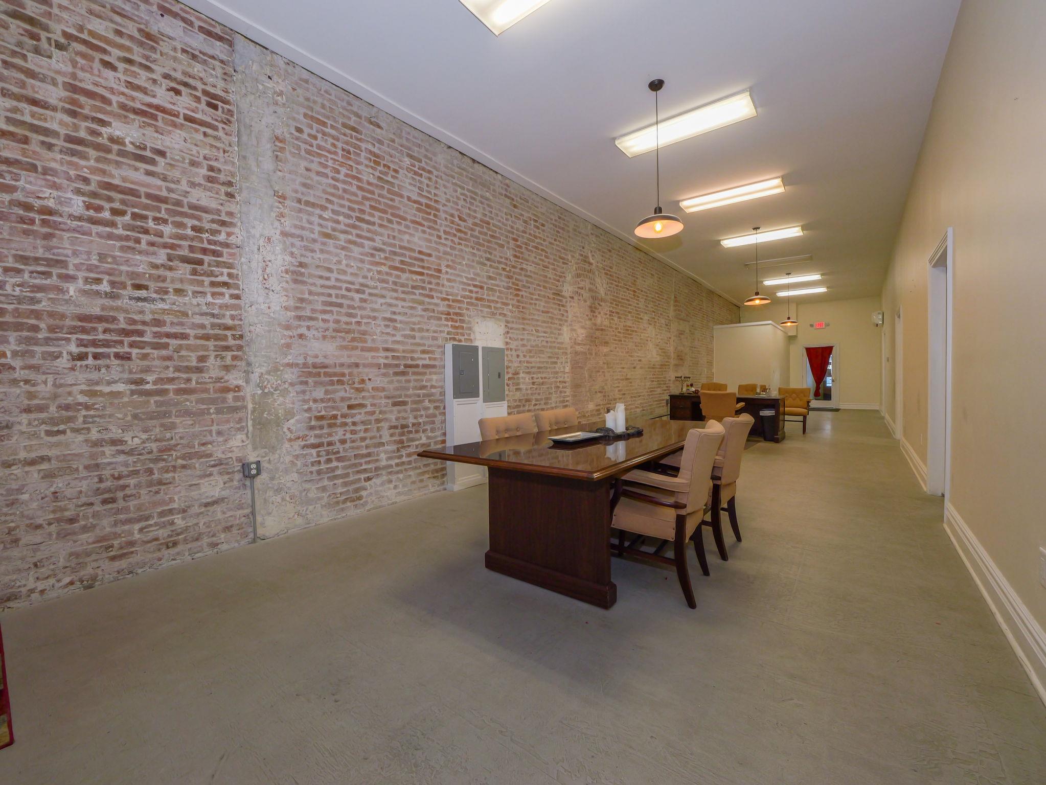 Office space with baseboards and brick wall