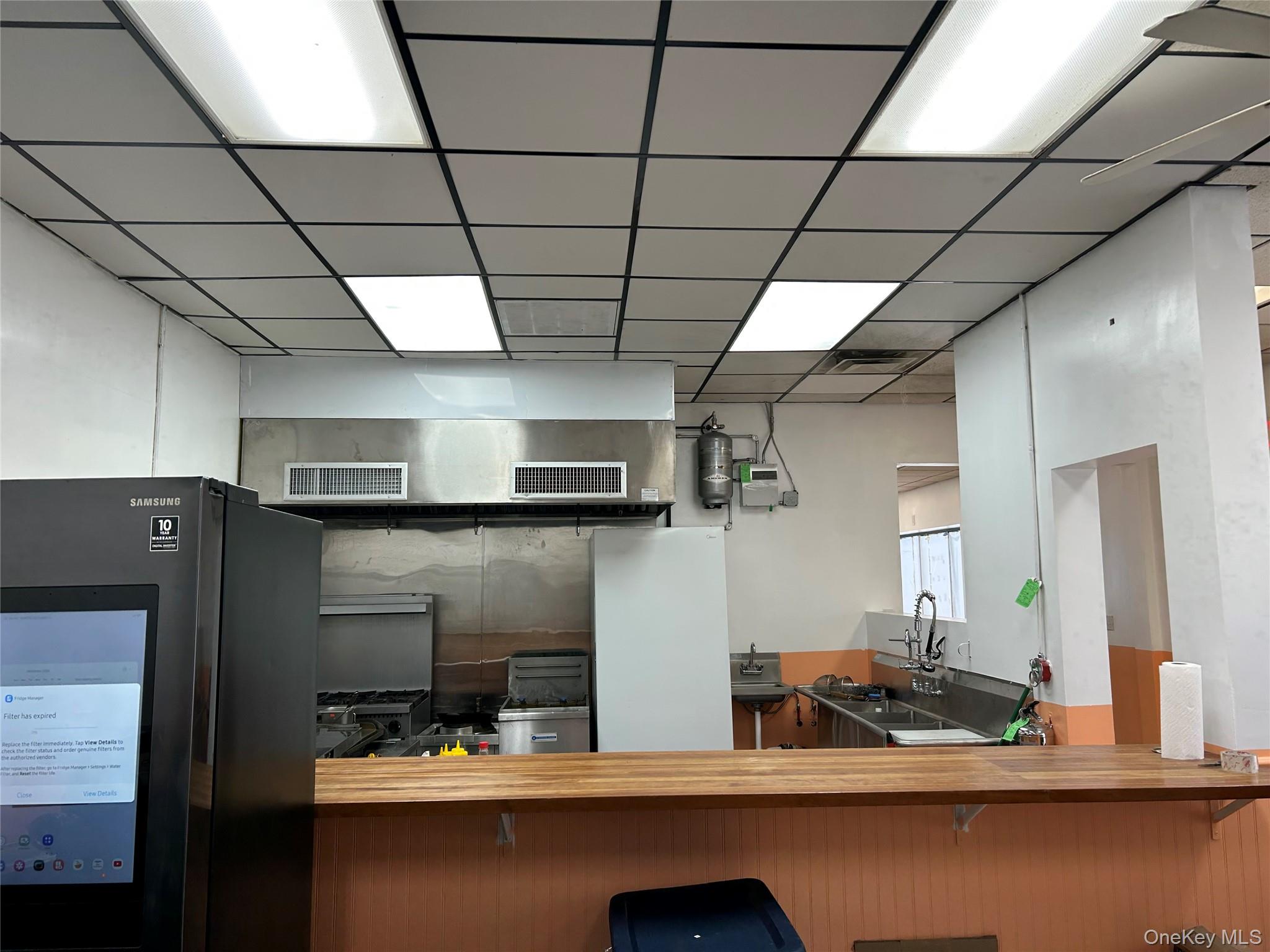 Kitchen with freestanding refrigerator, butcher block countertops, and a drop ceiling