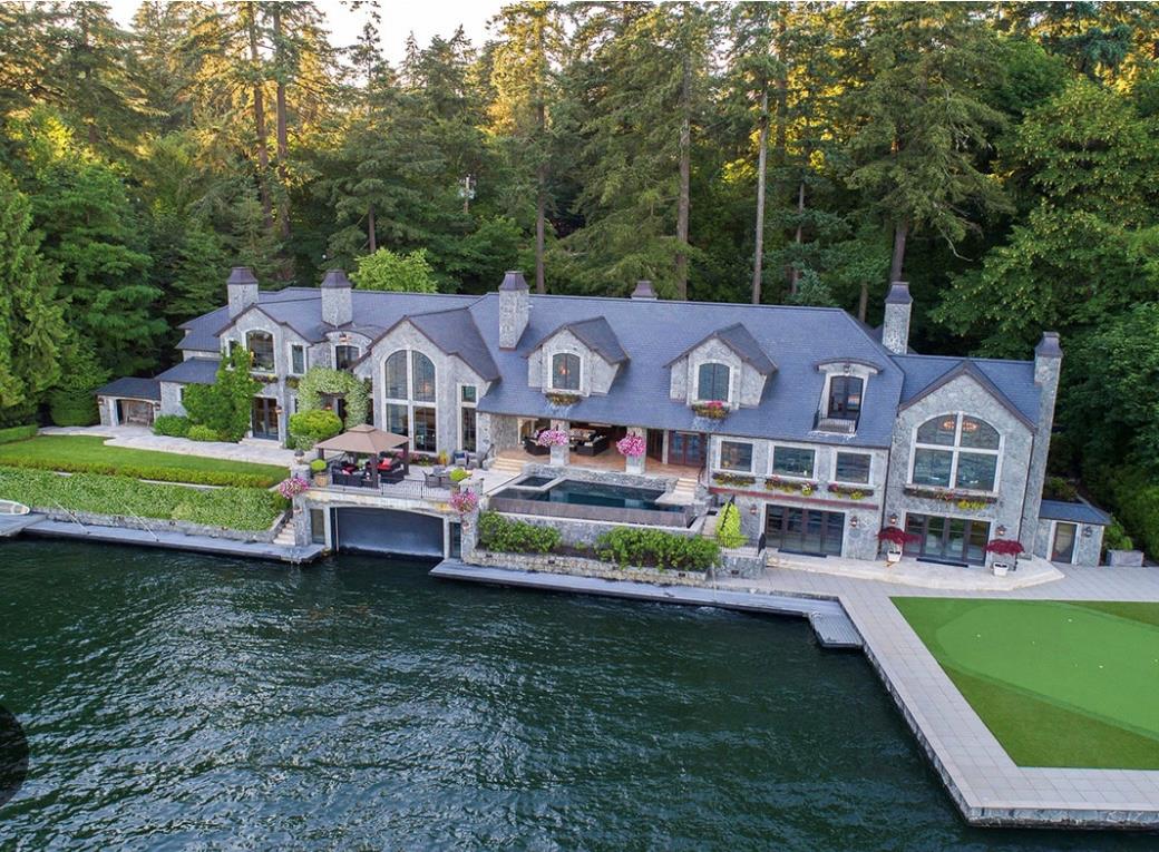 Rear view of house with a chimney, a patio area, a water view, and a forest view