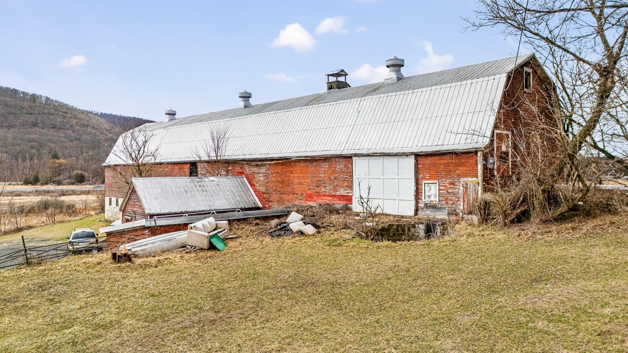 Rear view of property featuring a barn, a yard, an outbuilding, a metal roof, and a mountain view