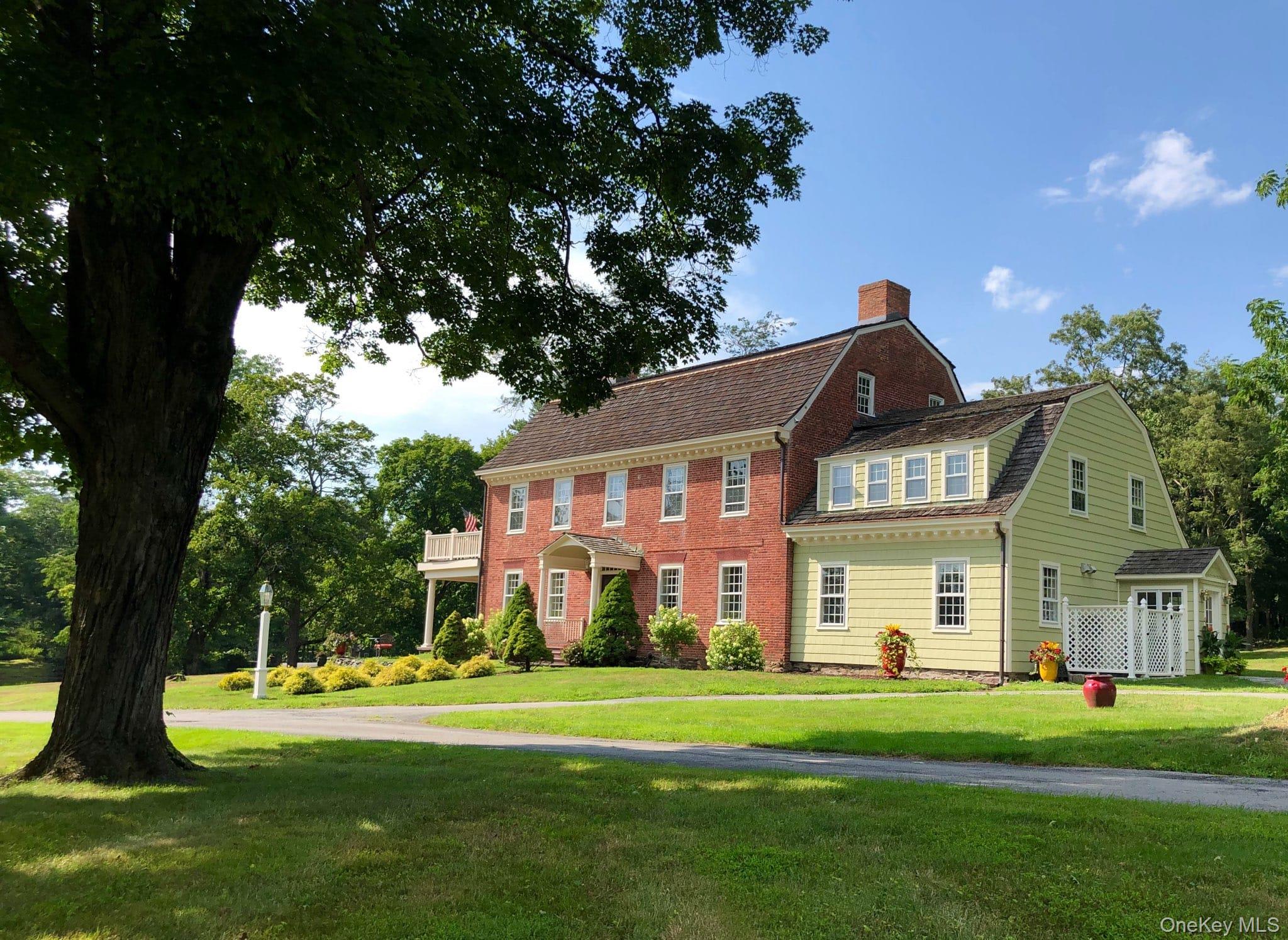 View of front of home with a gambrel roof, a front yard, a chimney, and roof with shingles