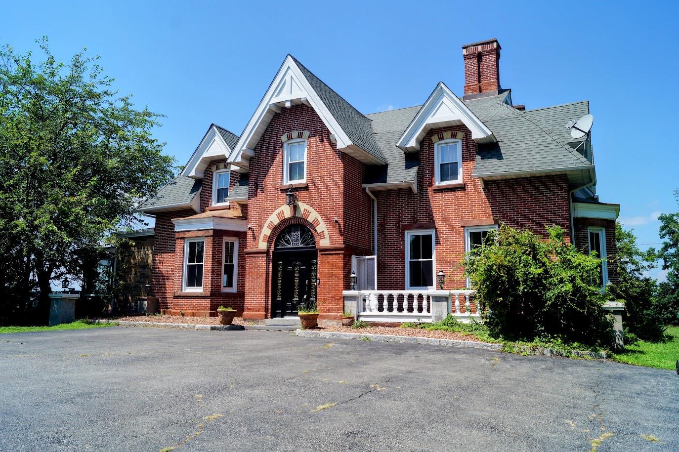View of front facade featuring brick siding, roof with shingles, and a chimney
