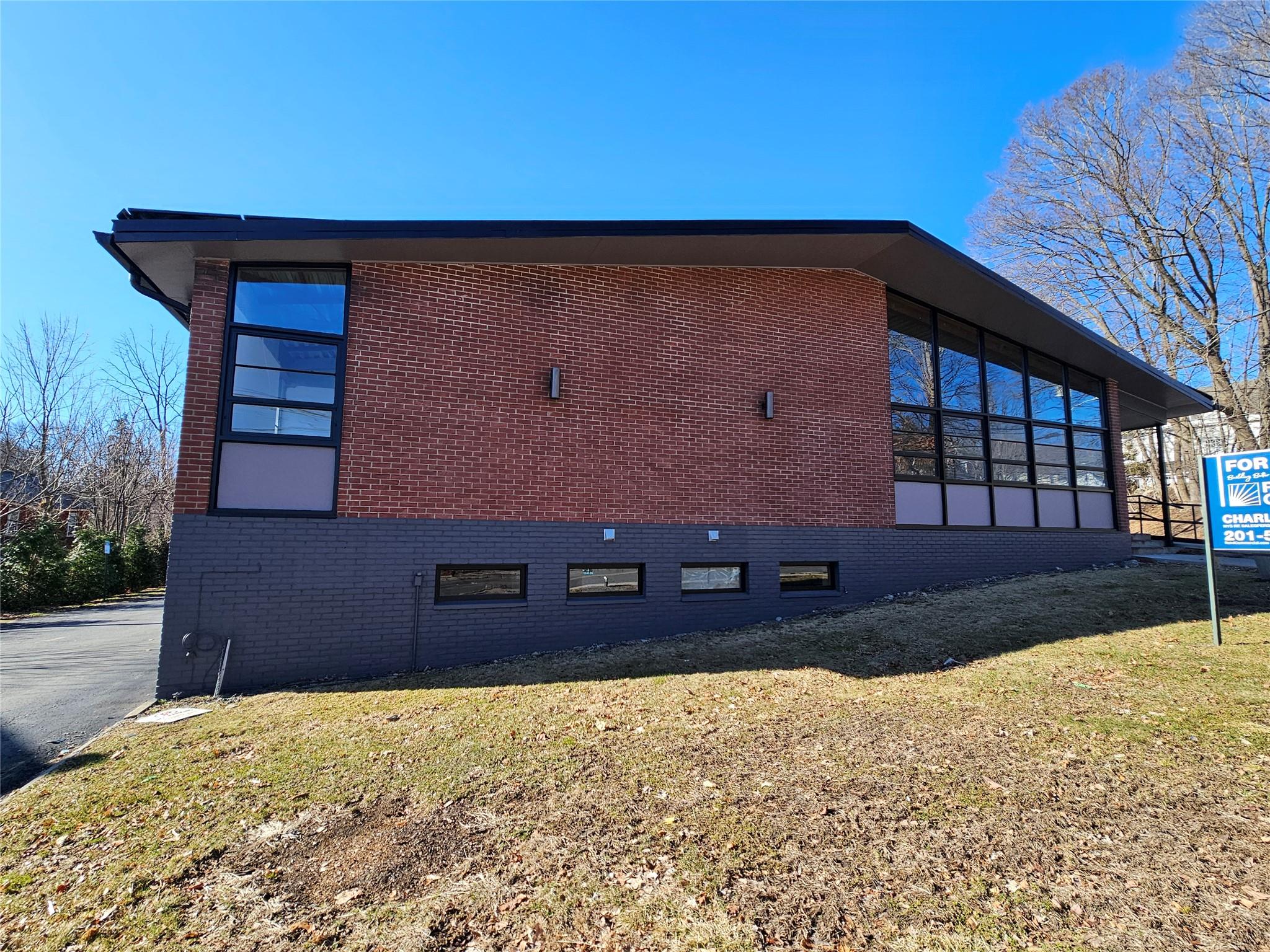 View of side of property featuring a lawn and brick siding