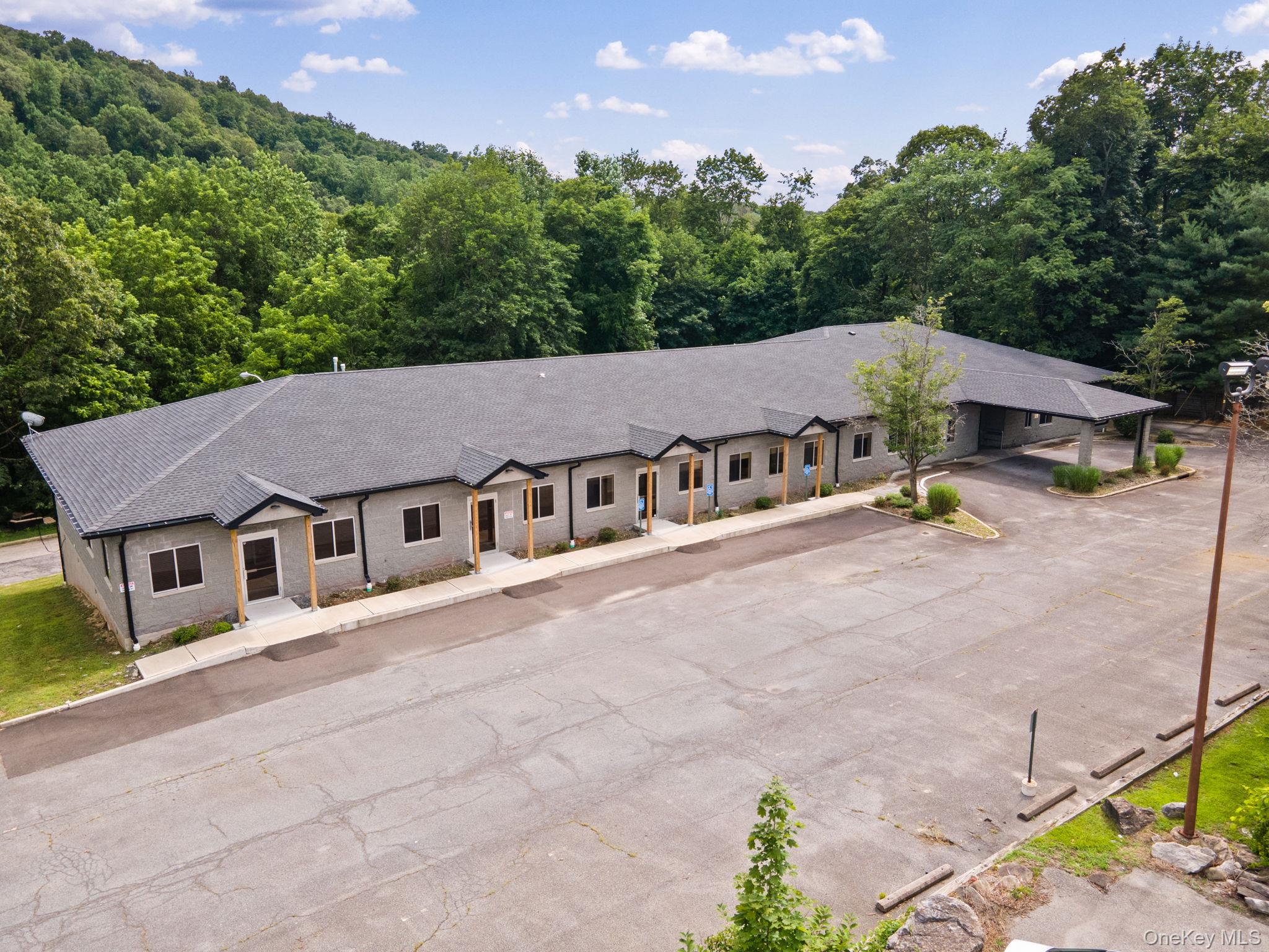 View of front of house featuring a view of trees and roof with shingles