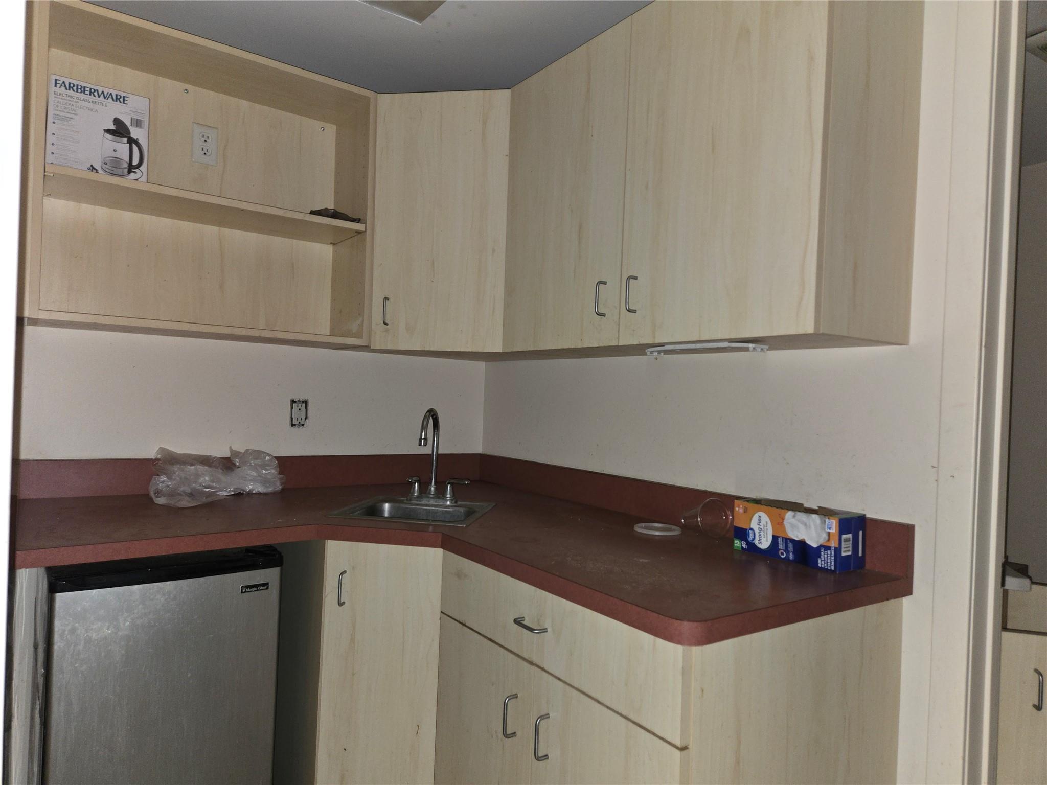 Kitchen with light brown cabinets, dark countertops, and fridge