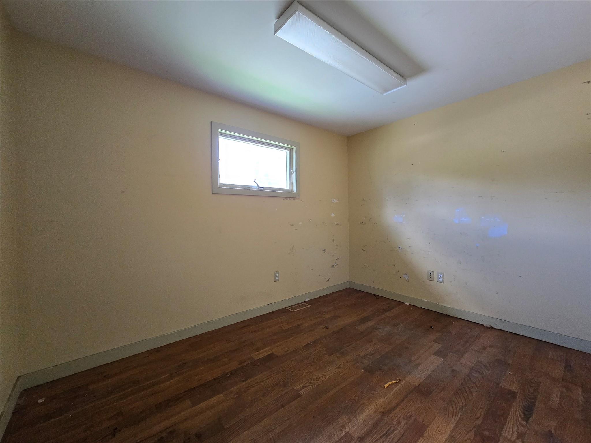 Spare room with dark wood-type flooring and baseboards