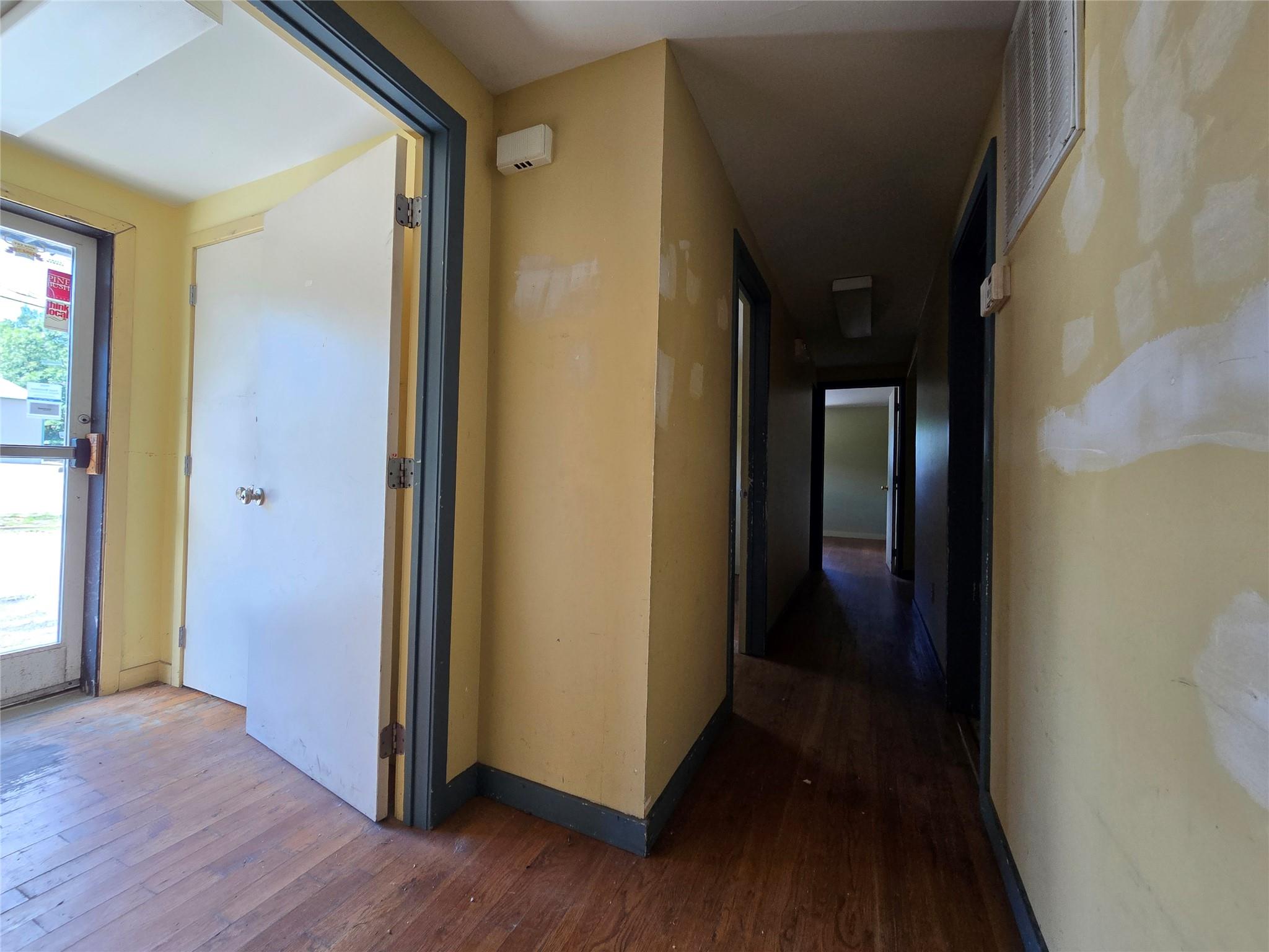 Corridor with wood-type flooring and baseboards