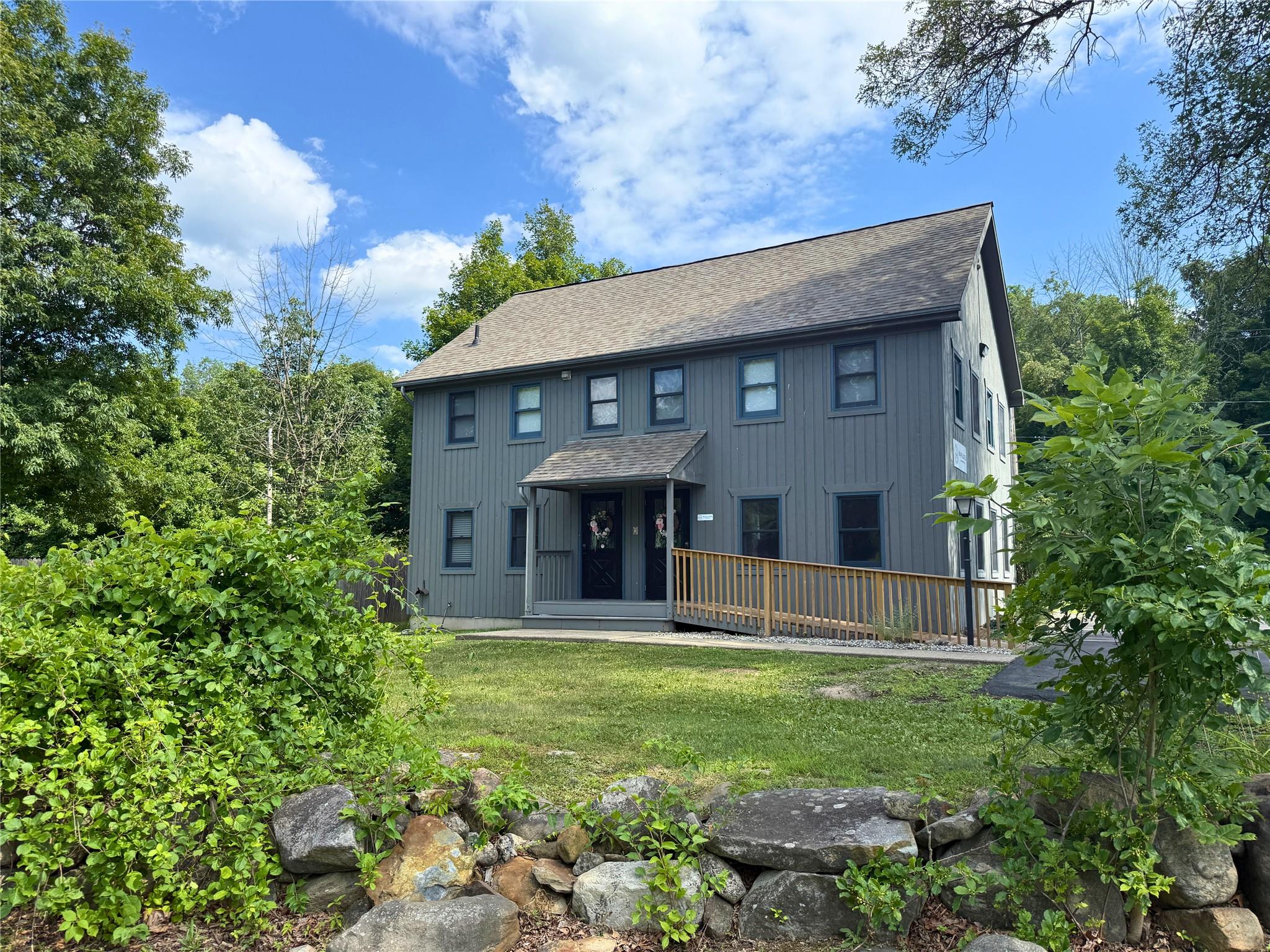 Back of property featuring a shingled roof, a lawn, and a deck