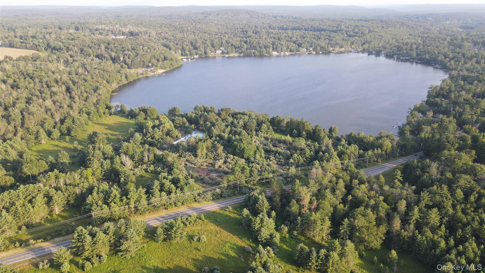 View of property location with a forest and a nearby body of water