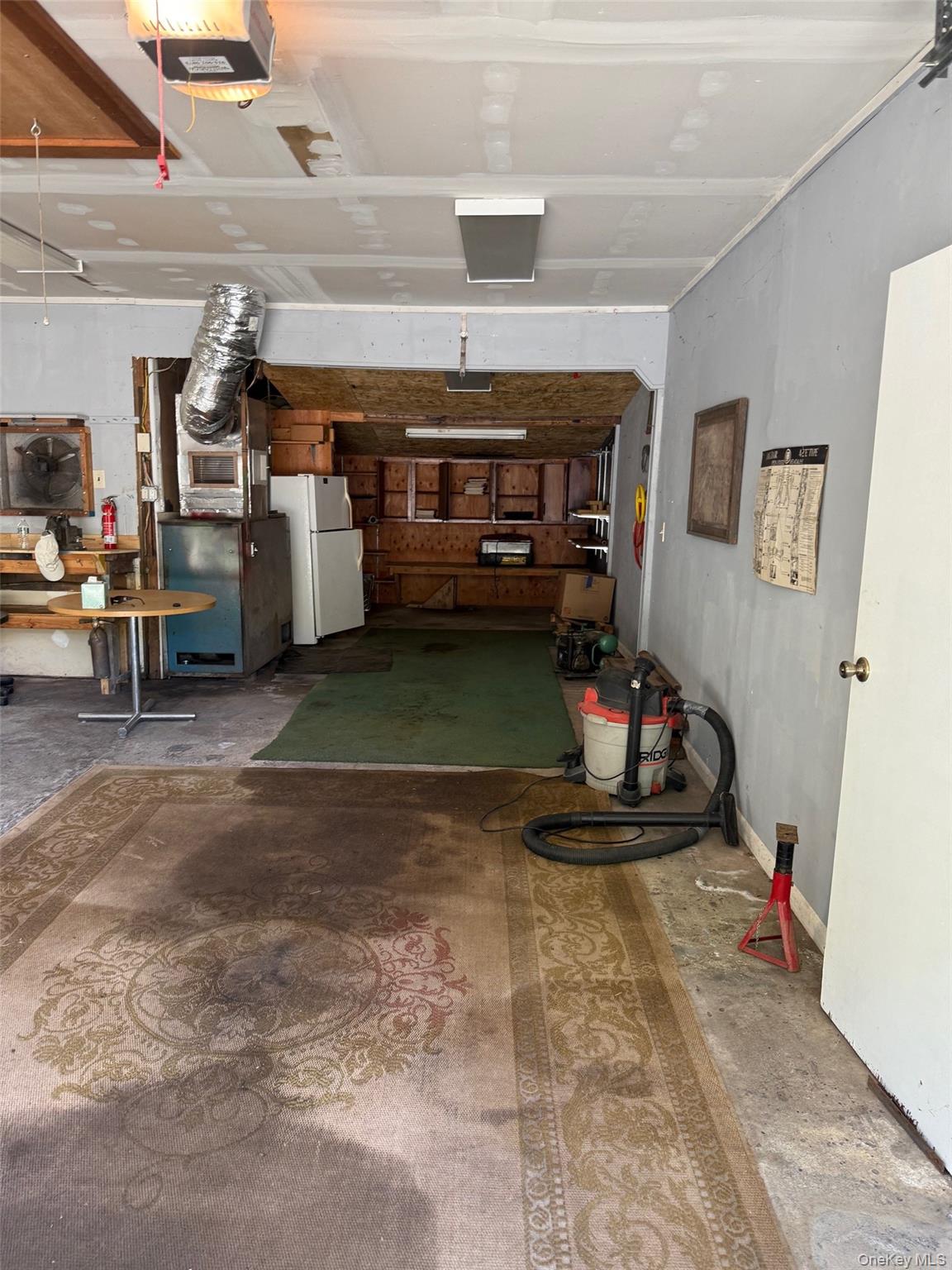Garage featuring a garage door opener, freestanding refrigerator, and heating unit