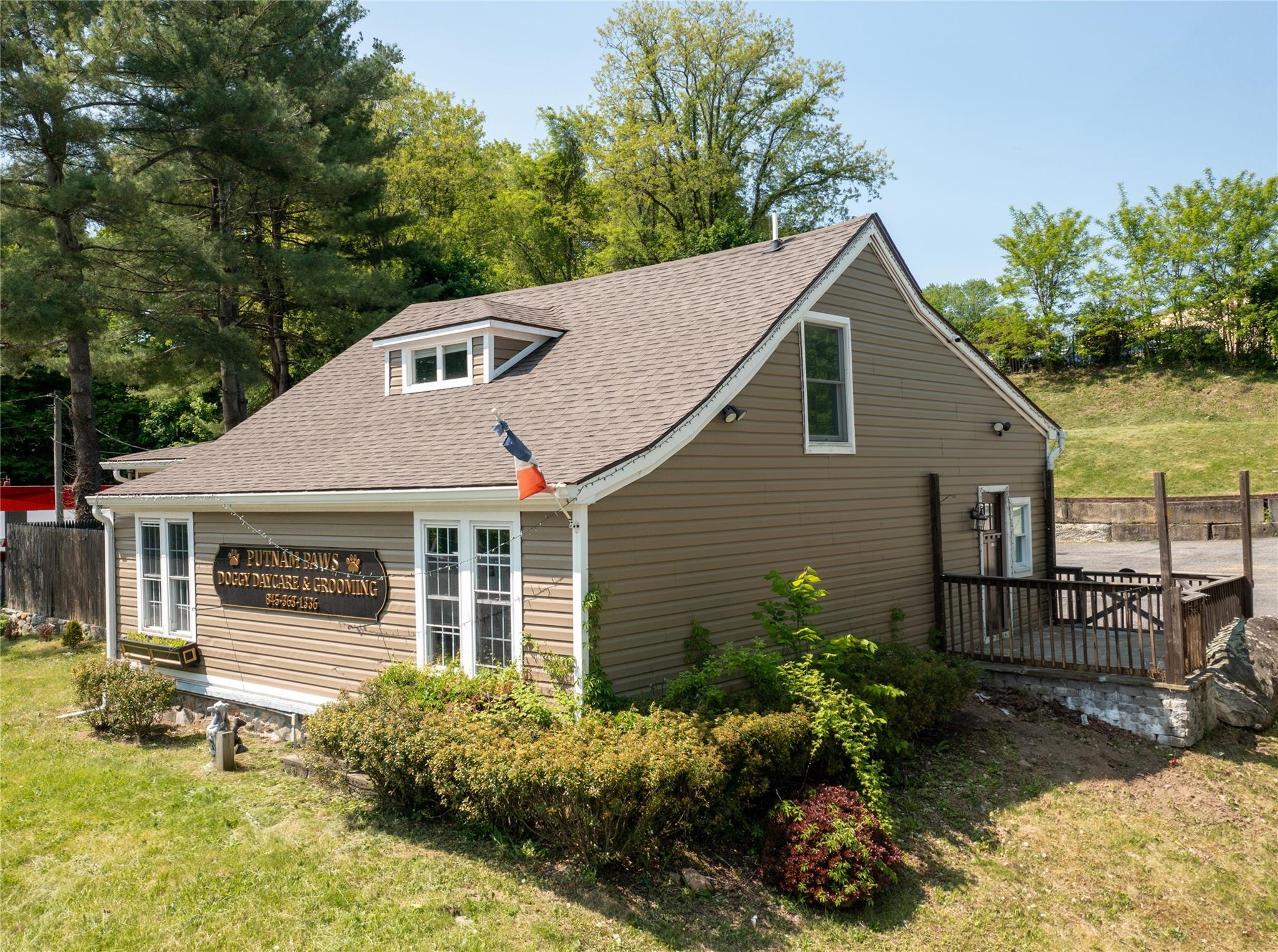 View of side of property featuring roof with shingles, a yard, and a deck