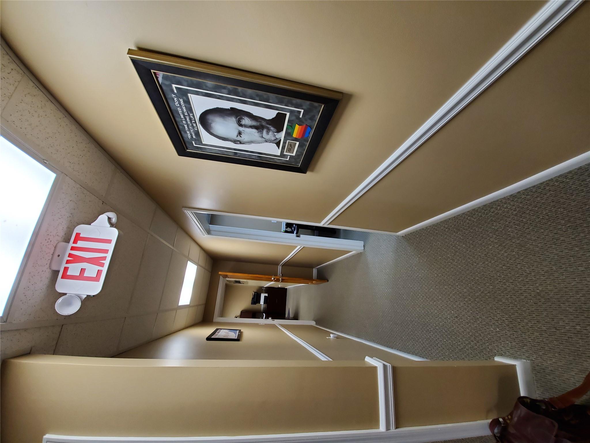 Corridor featuring a drop ceiling and carpet