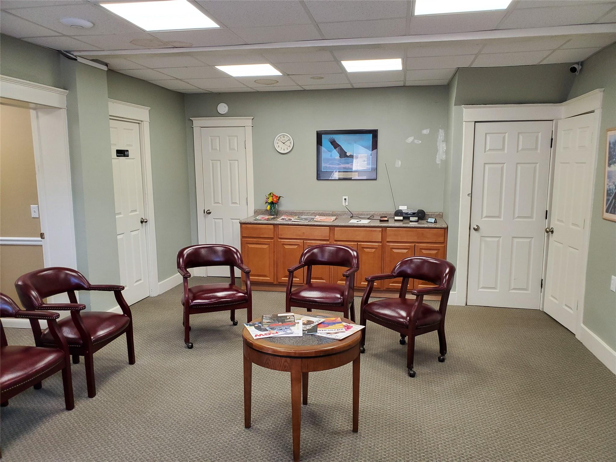 Sitting room with a paneled ceiling and carpet flooring