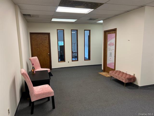 Living area featuring a paneled ceiling and carpet floors