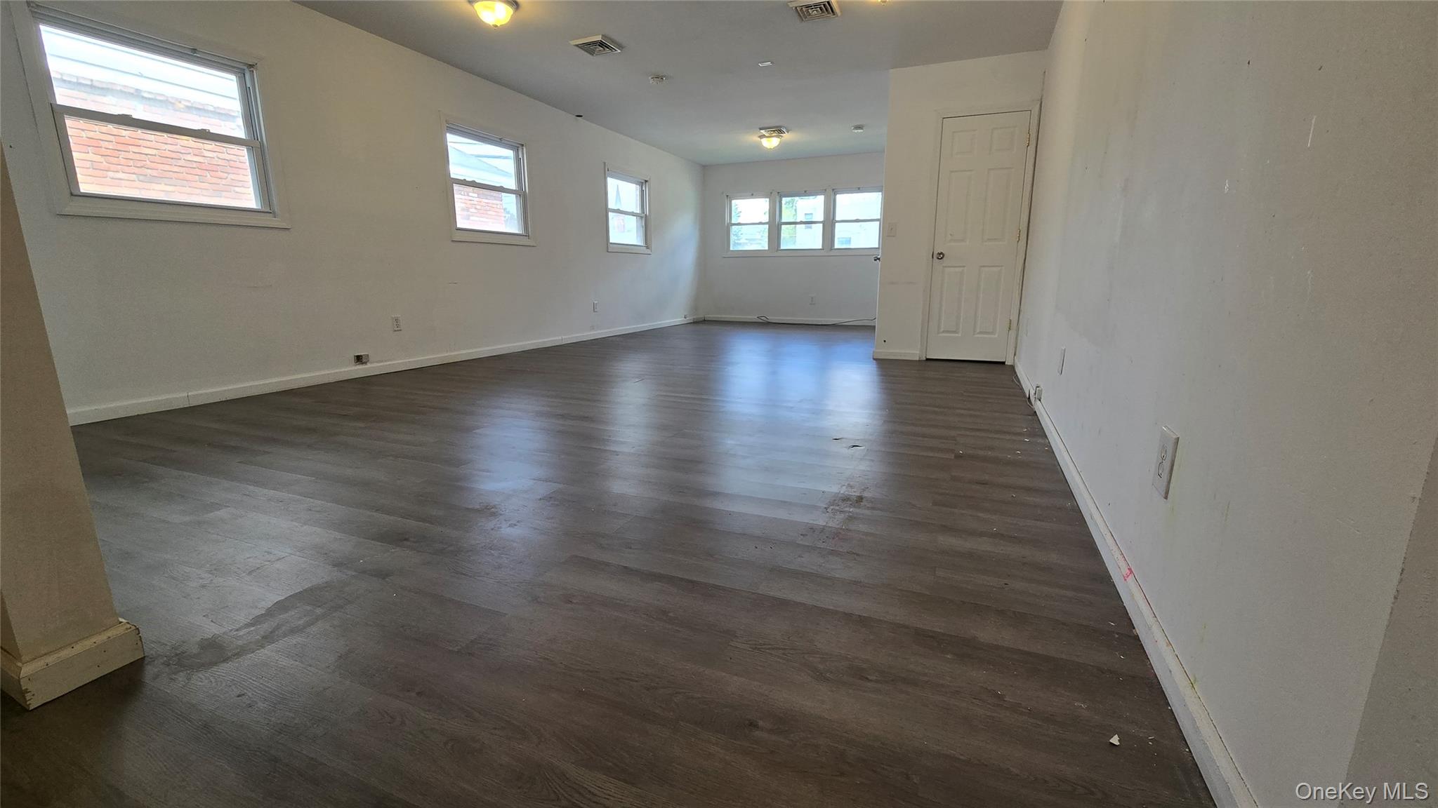 Spare room featuring baseboards and dark wood-style floors