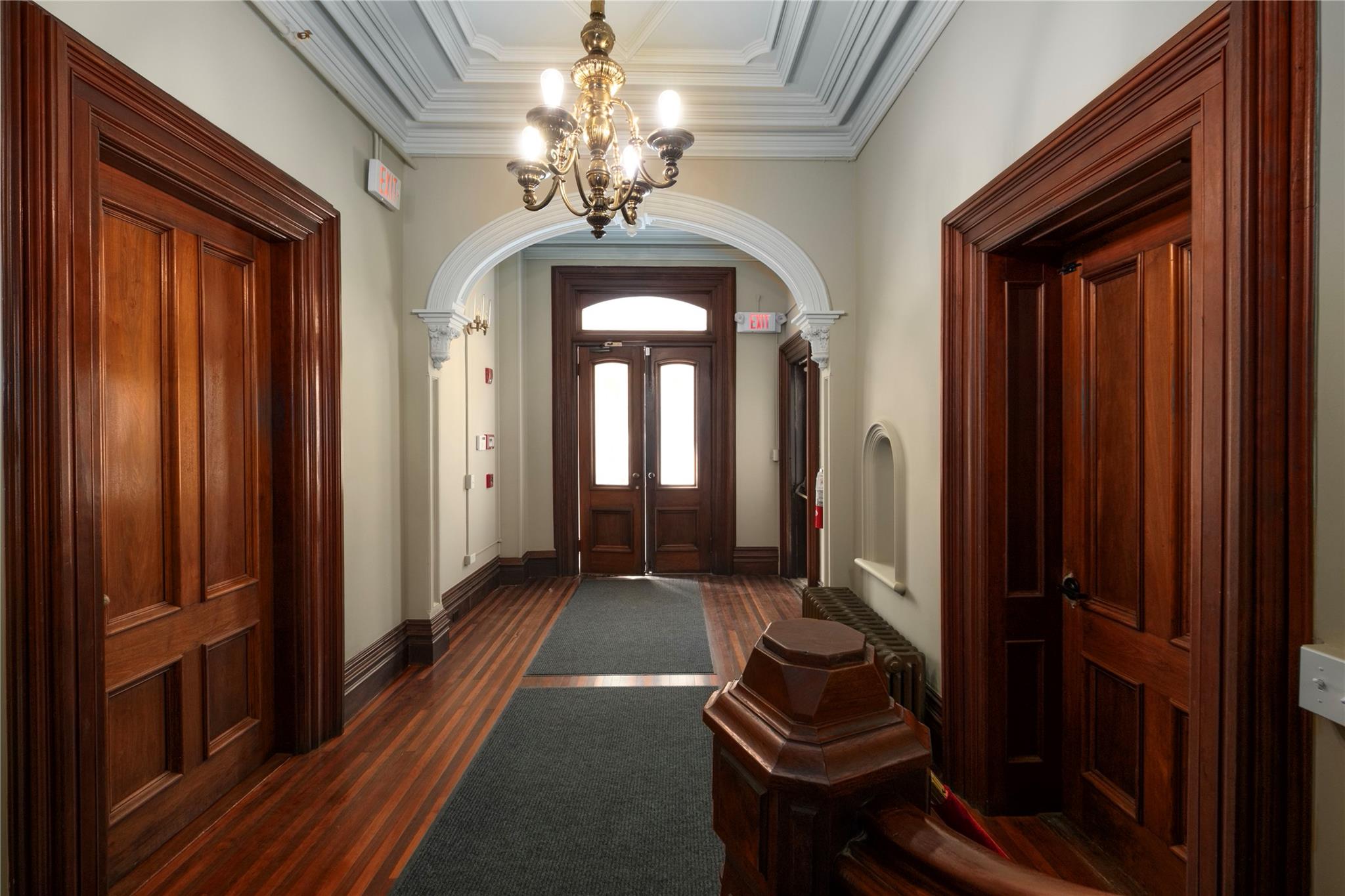 Entrance foyer featuring arched walkways, a chandelier, ornamental molding, and dark wood-style floors