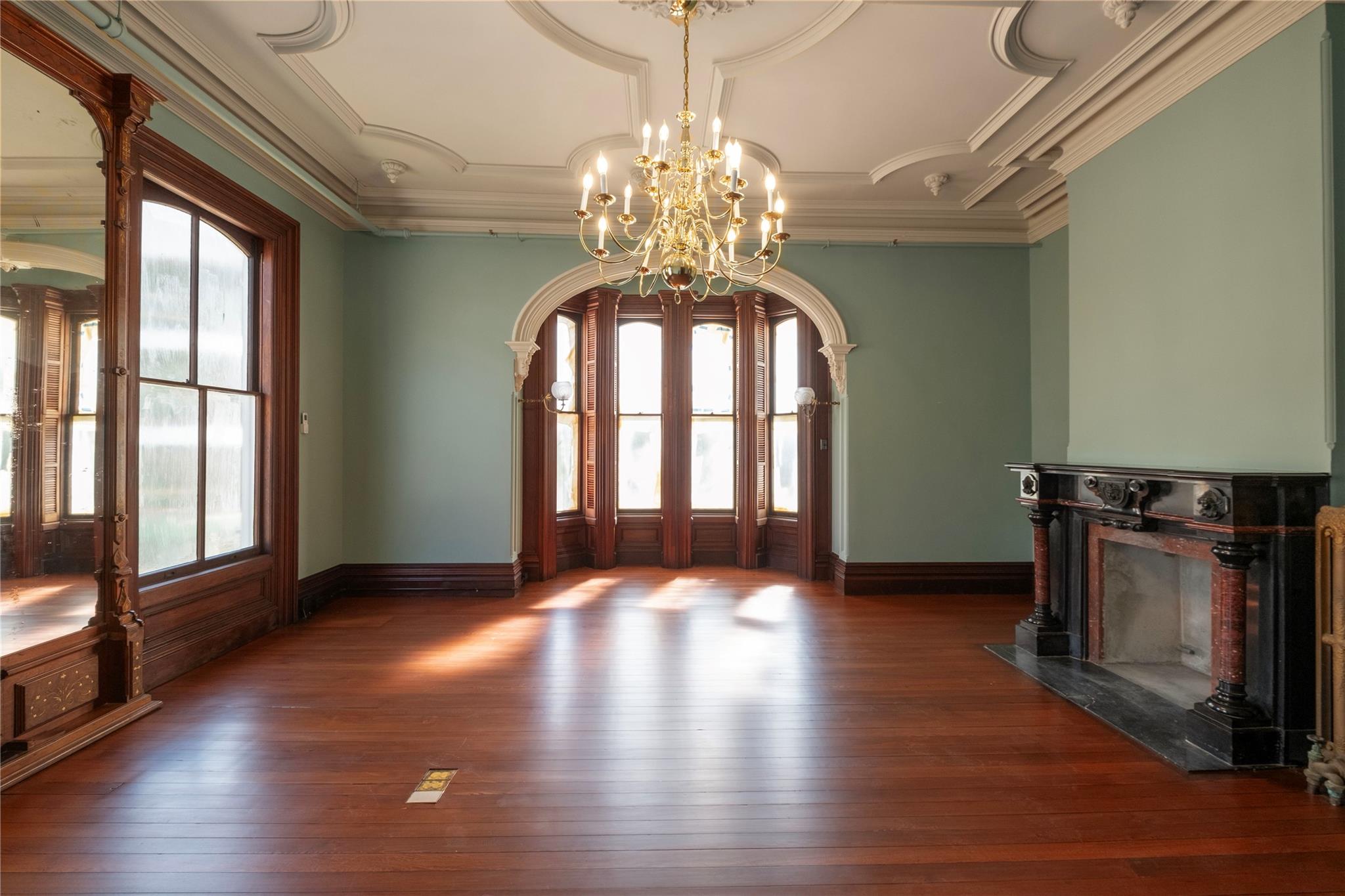 Foyer entrance with hardwood / wood-style floors, a chandelier, a premium fireplace, french doors, and arched walkways