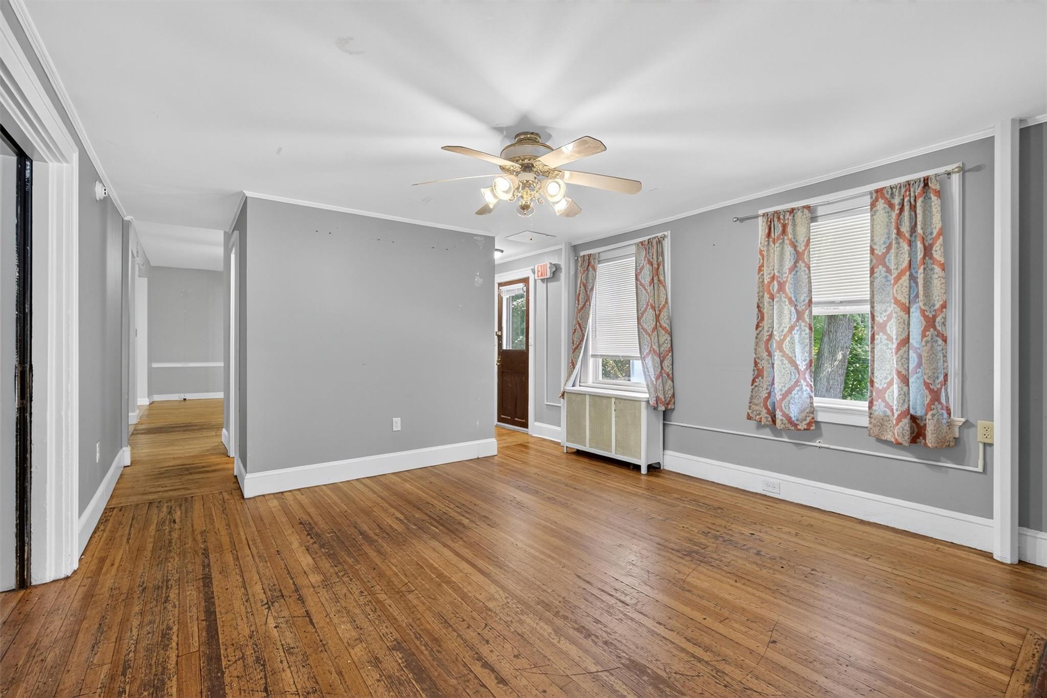 Unfurnished room with ornamental molding, hardwood / wood-style floors, a ceiling fan, and radiator