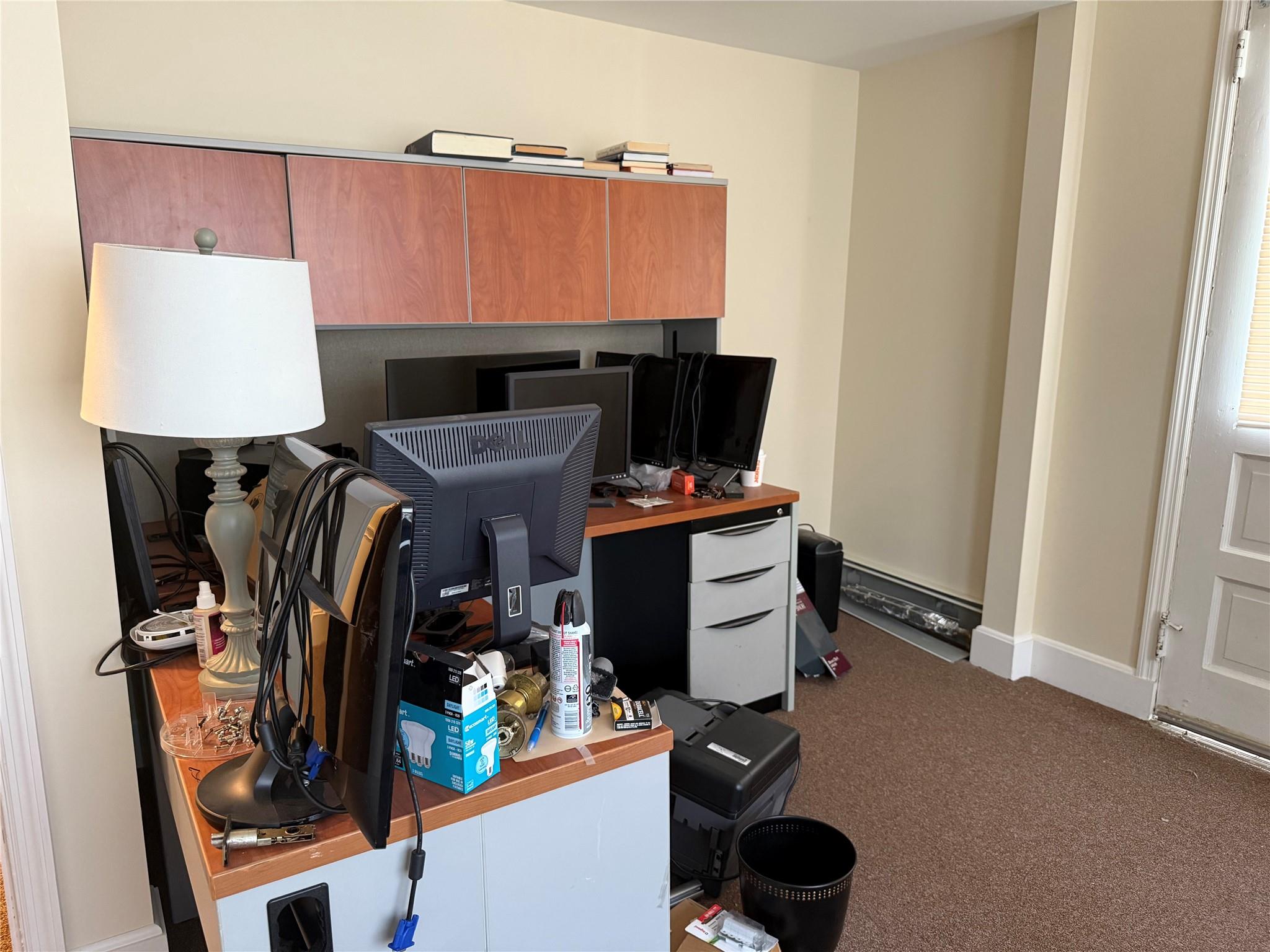 Carpeted home office featuring baseboards