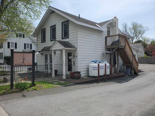 View of property exterior with a chimney, stairway, and roof with shingles