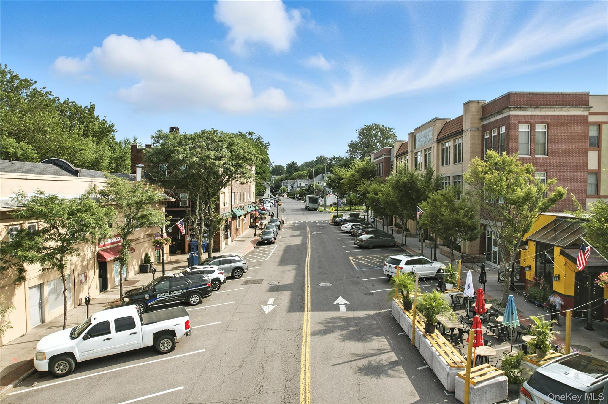 View of asphalt road featuring sidewalks and street lights