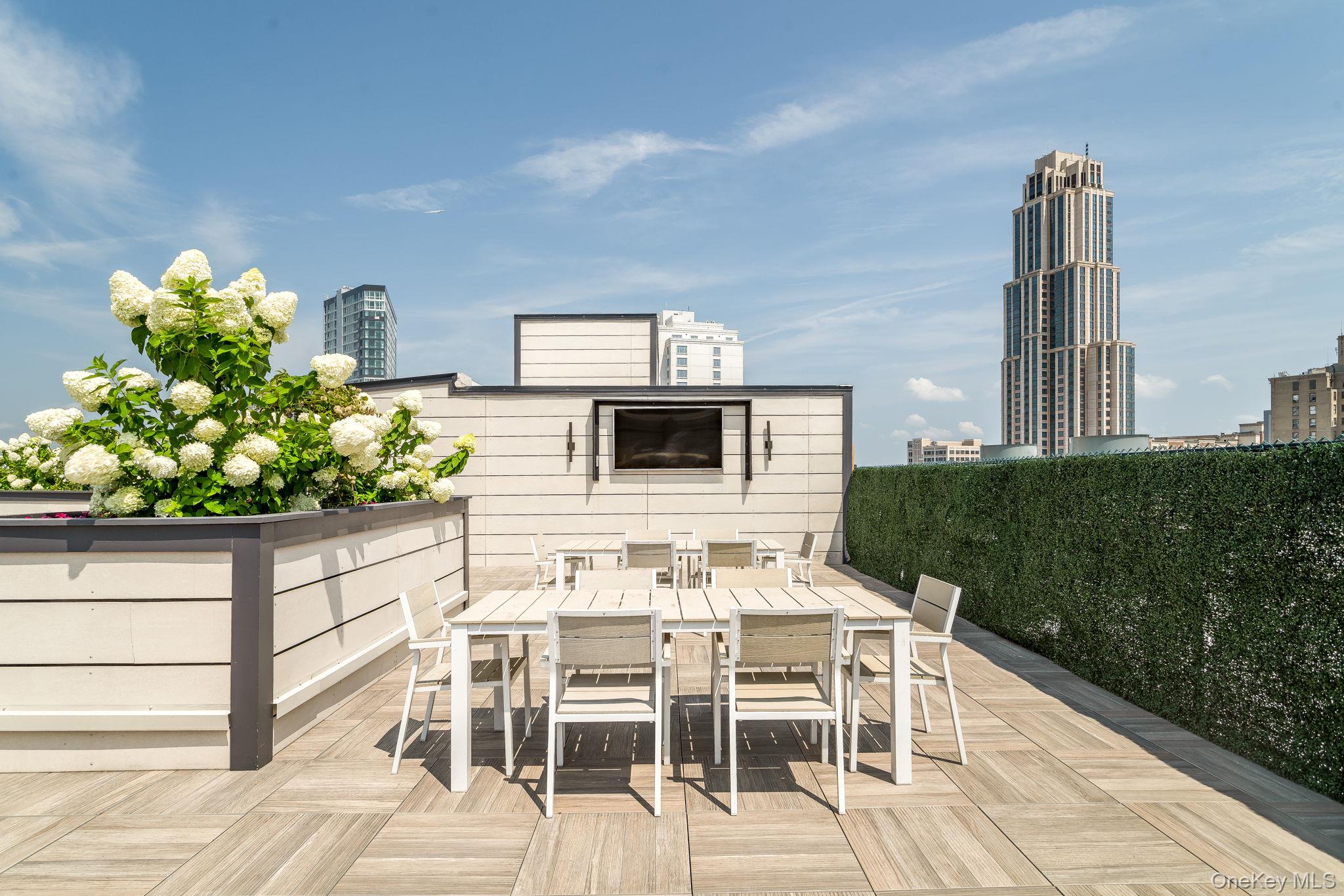 Wooden terrace featuring outdoor dining area and a city view
