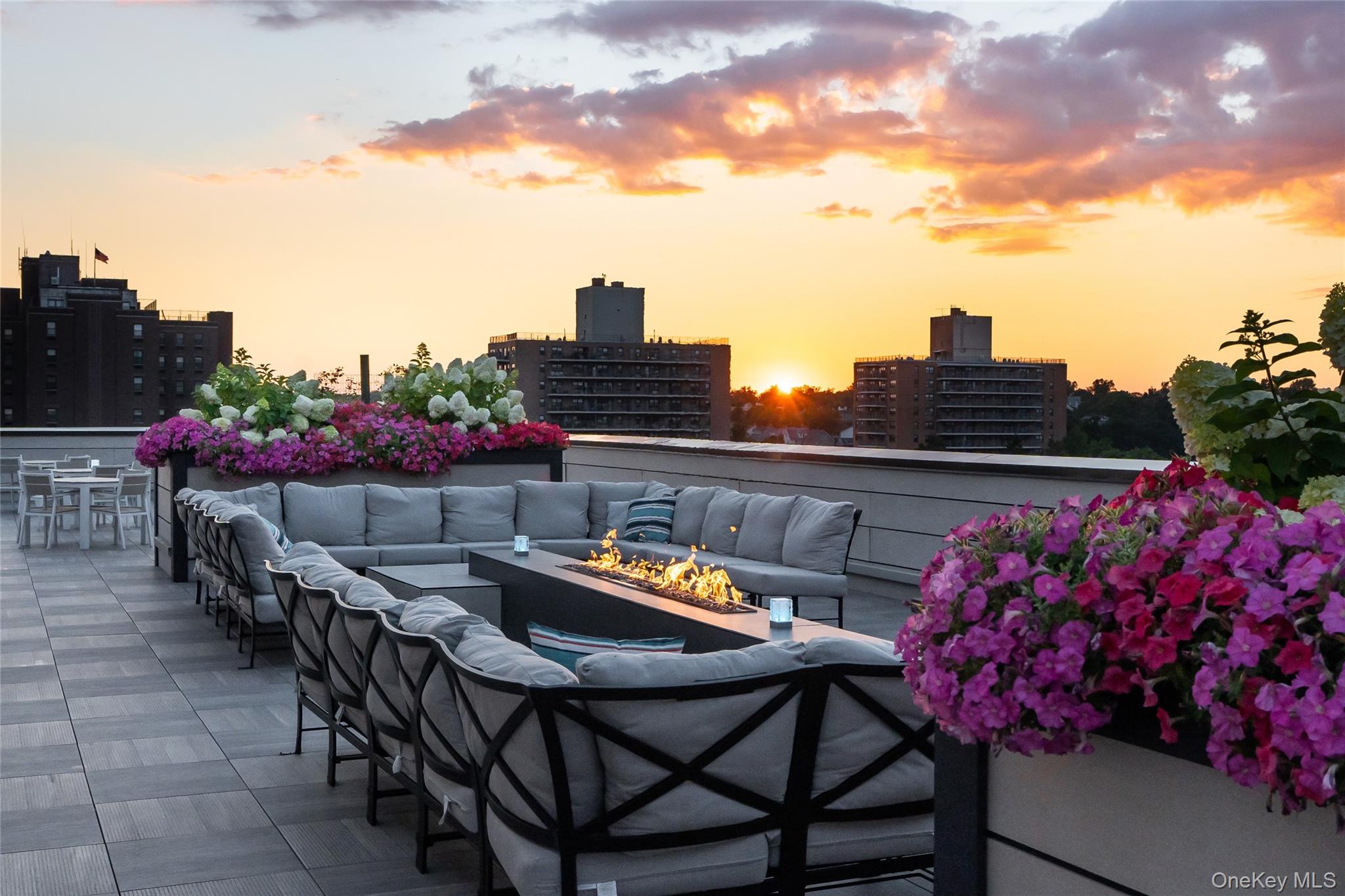Patio terrace at dusk featuring an outdoor living space with a fire pit, a city view, and a patio area