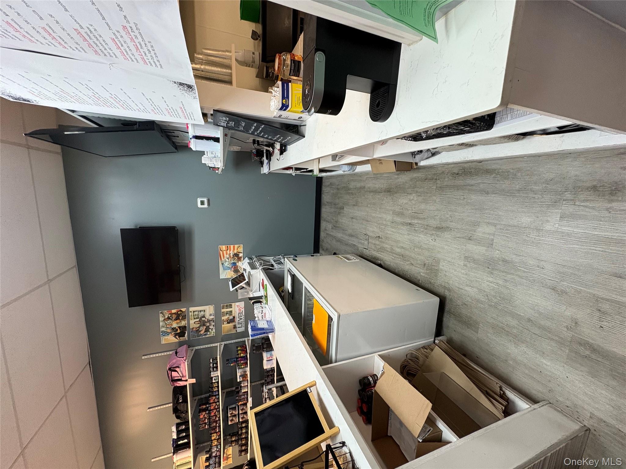 Kitchen featuring a drop ceiling, light wood-style floors, light countertops, and freestanding refrigerator