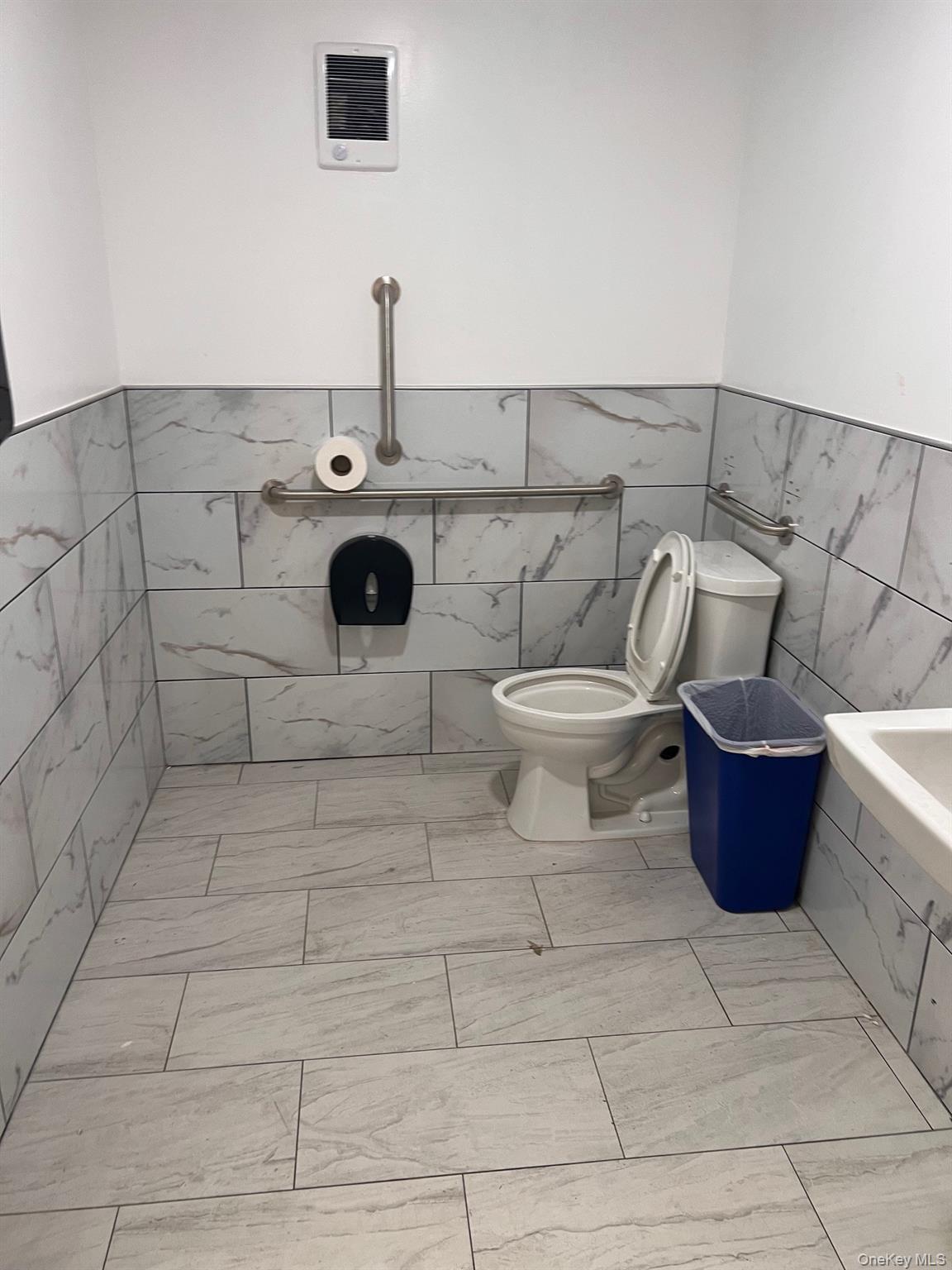 Full bath featuring tile walls, wainscoting, and tiled bath