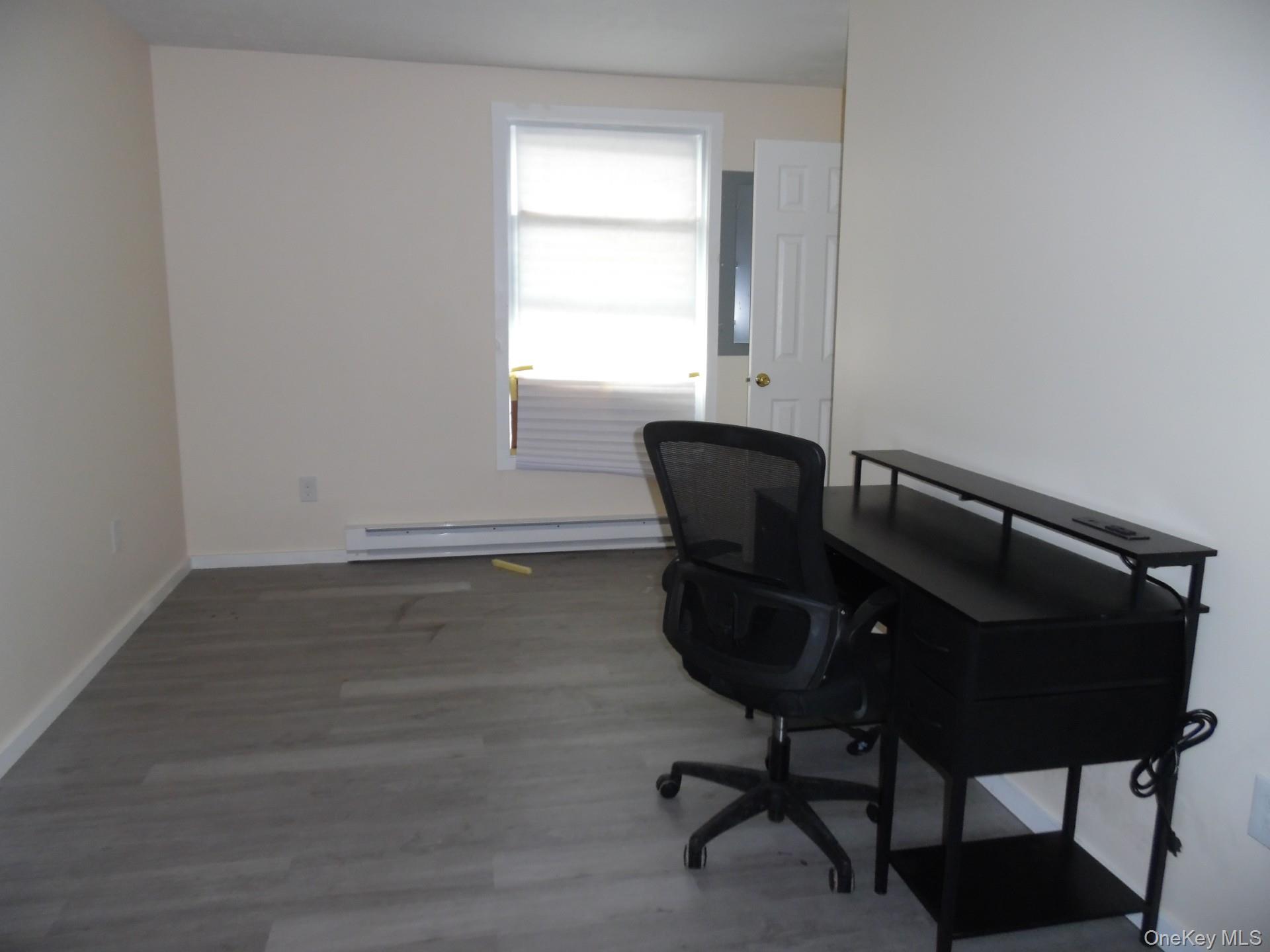 Office space featuring wood finished floors and baseboard heating