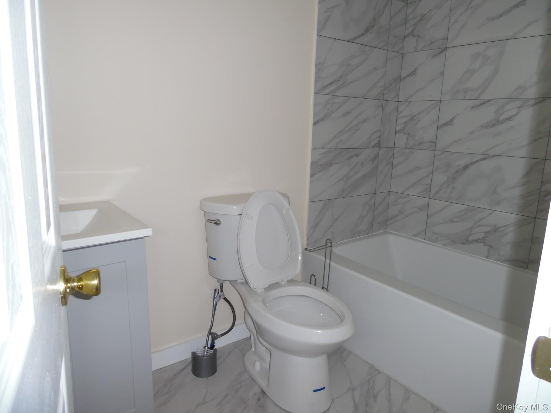 Bathroom featuring vanity, shower / washtub combination, and light marble finish floors