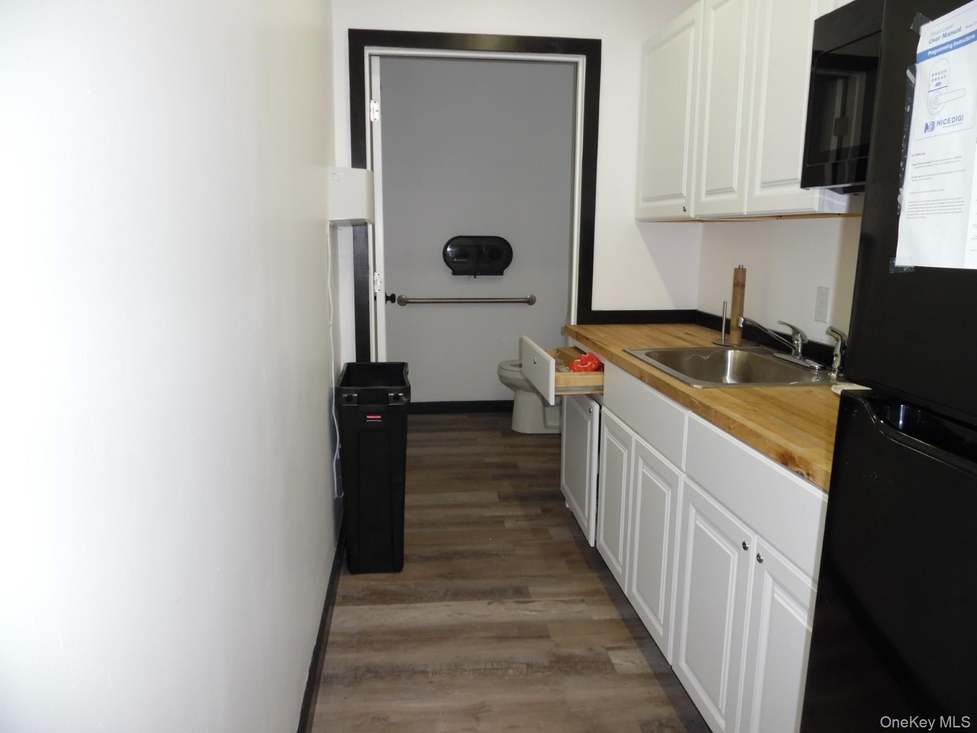 Kitchen with white cabinets, black appliances, and dark wood-style flooring