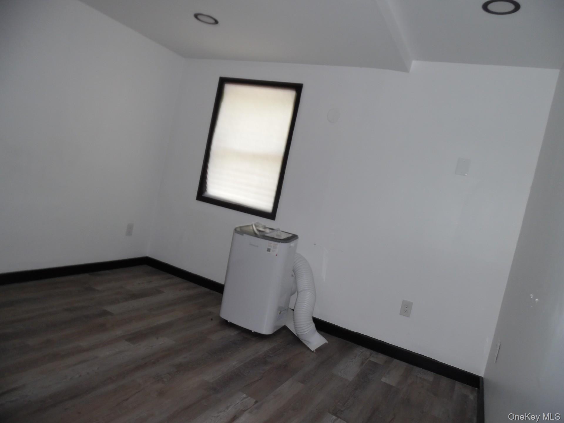 Empty room featuring dark wood-type flooring and recessed lighting