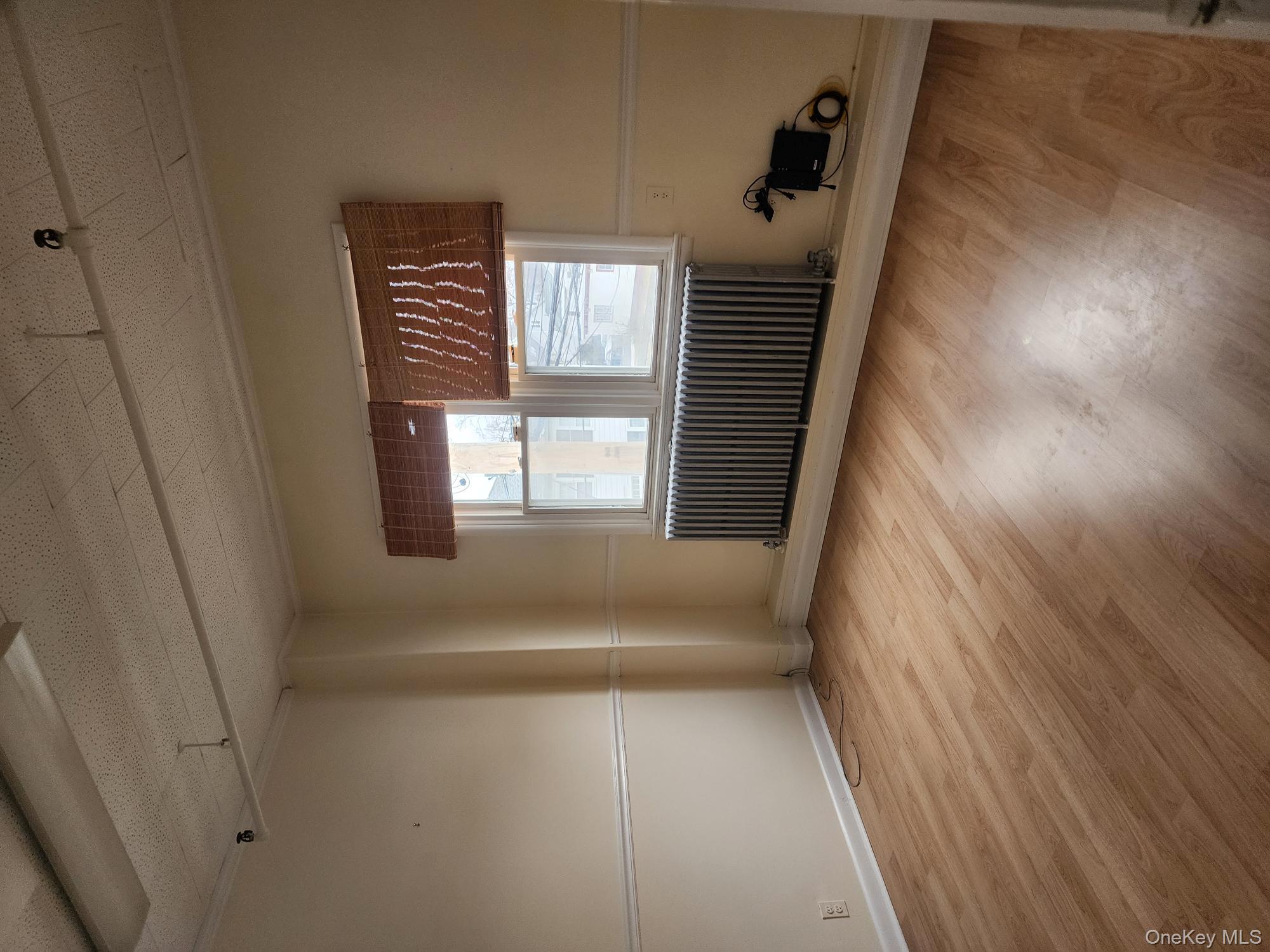Unfurnished room featuring radiator and wood finished floors