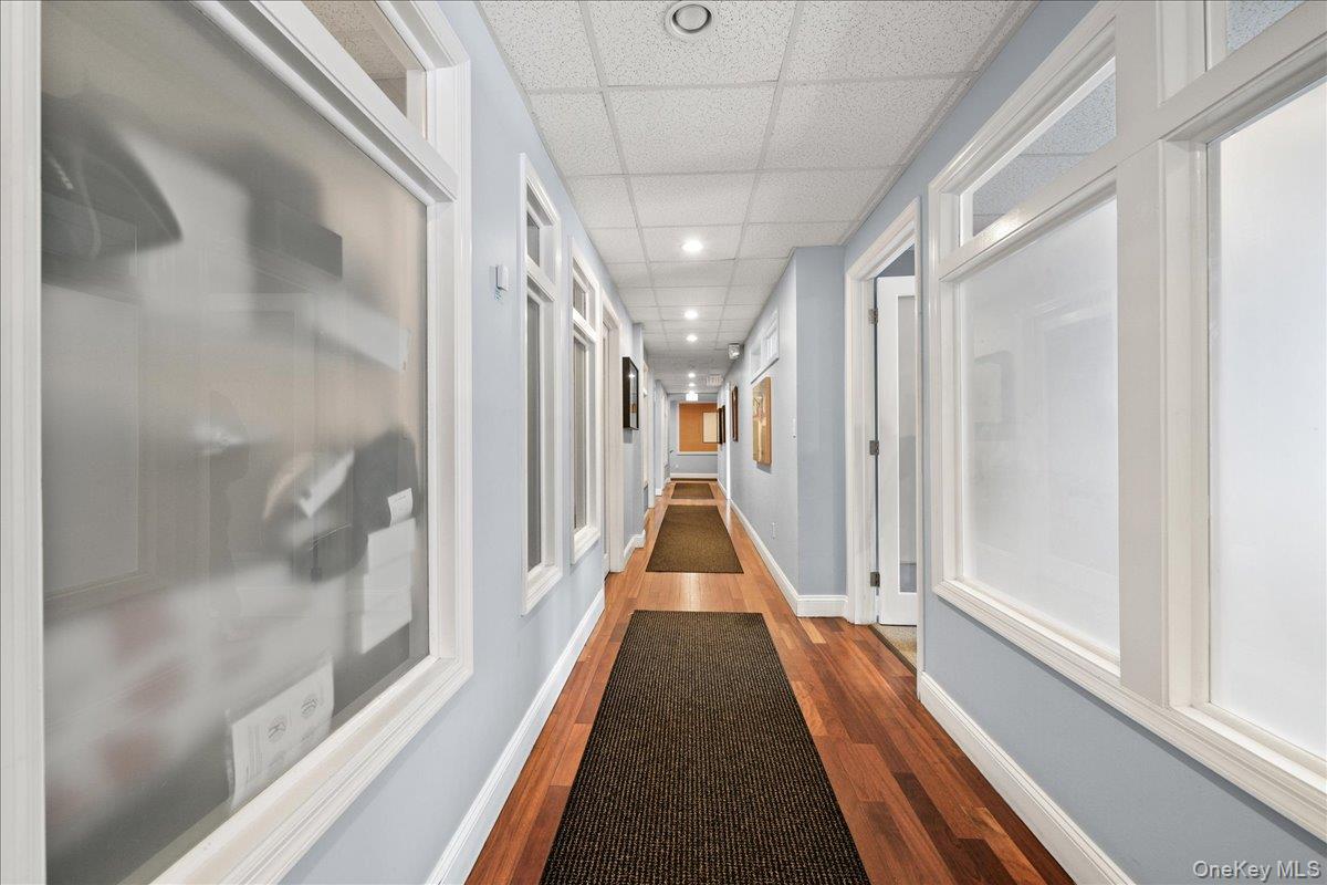Corridor with a drop ceiling, recessed lighting, and dark wood finished floors