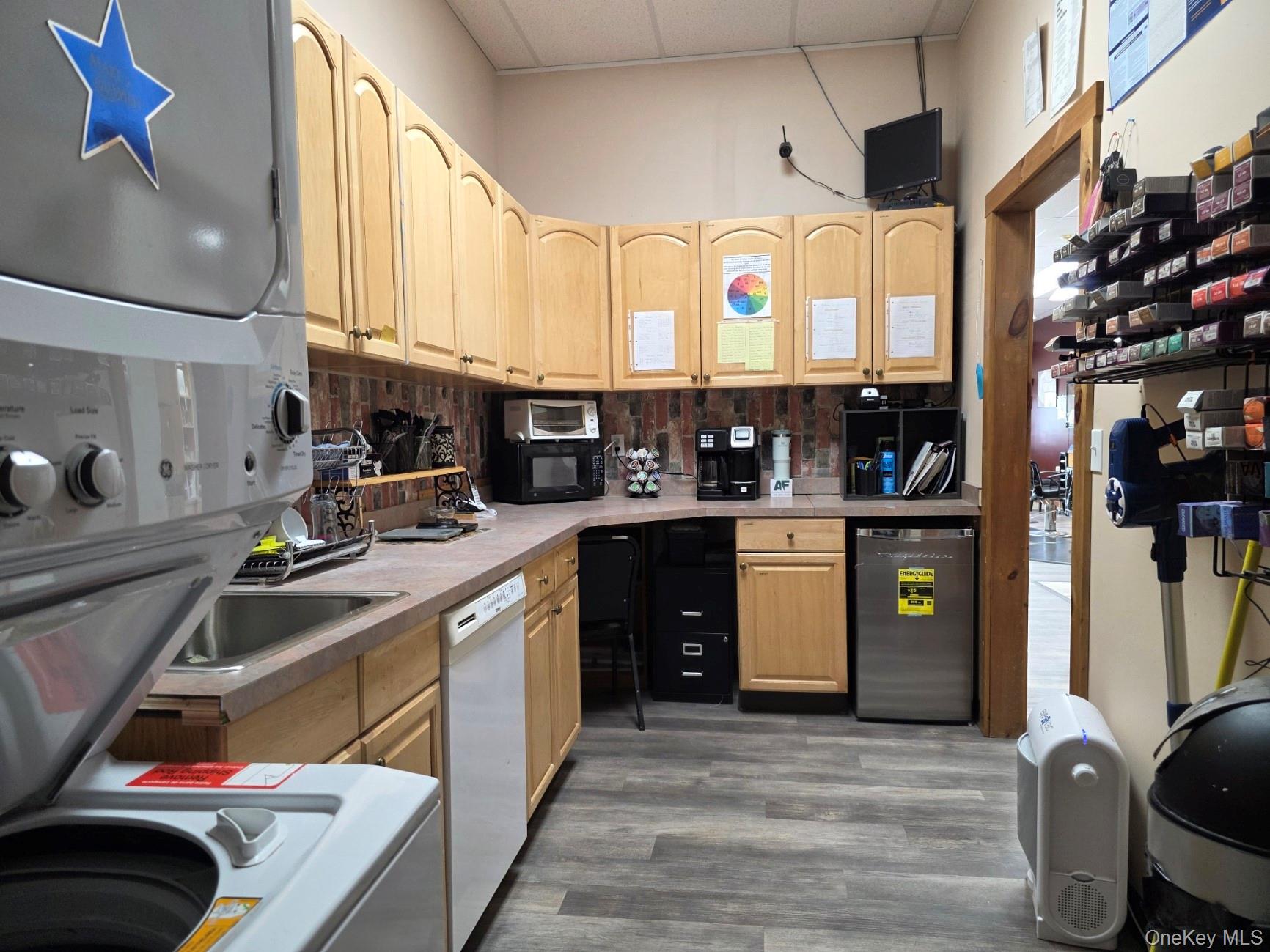 Kitchen featuring a paneled ceiling, light countertops, light brown cabinetry, white appliances, and backsplash