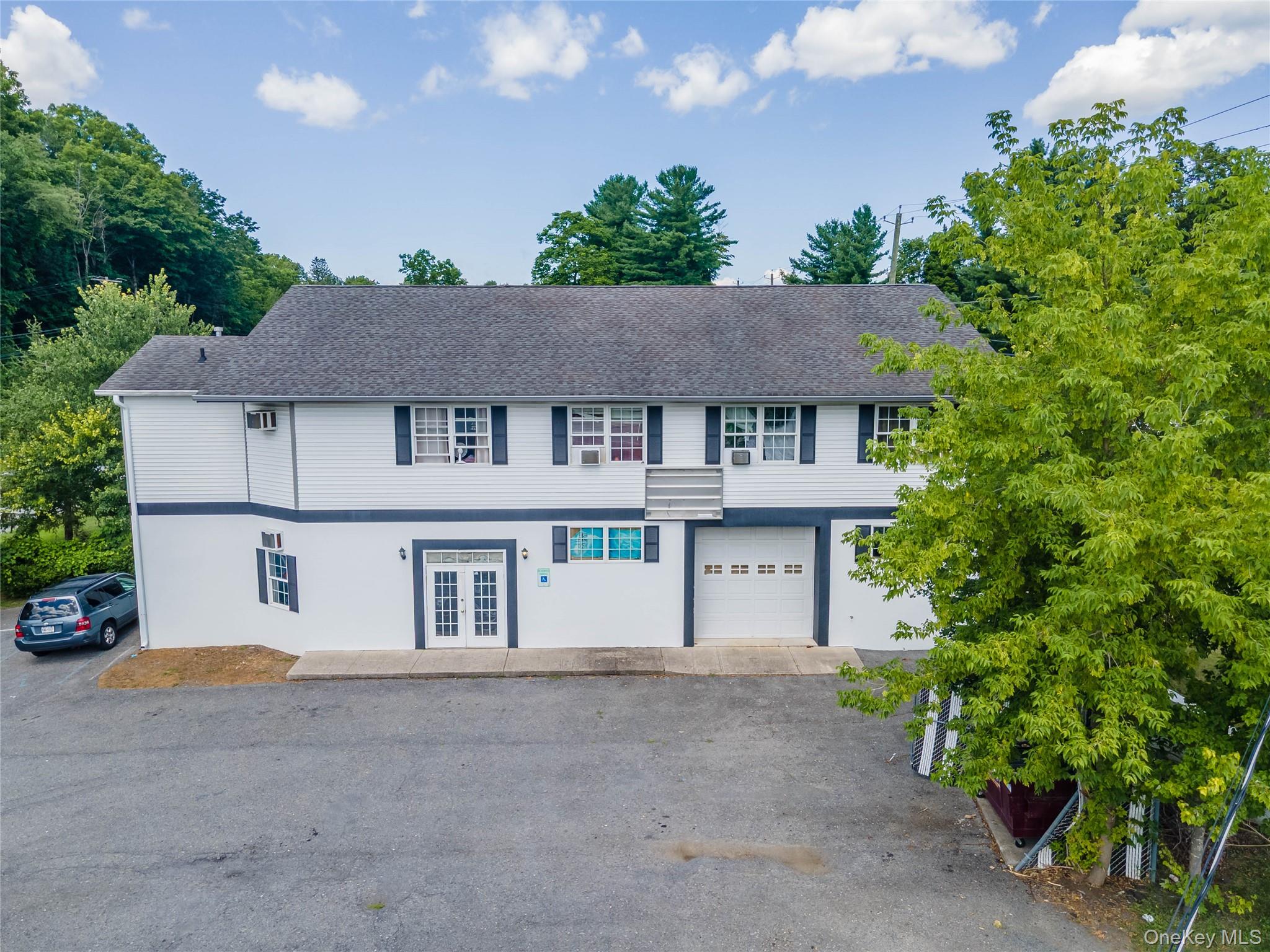 View of front of house with french doors, roof with shingles, an attached garage, and driveway