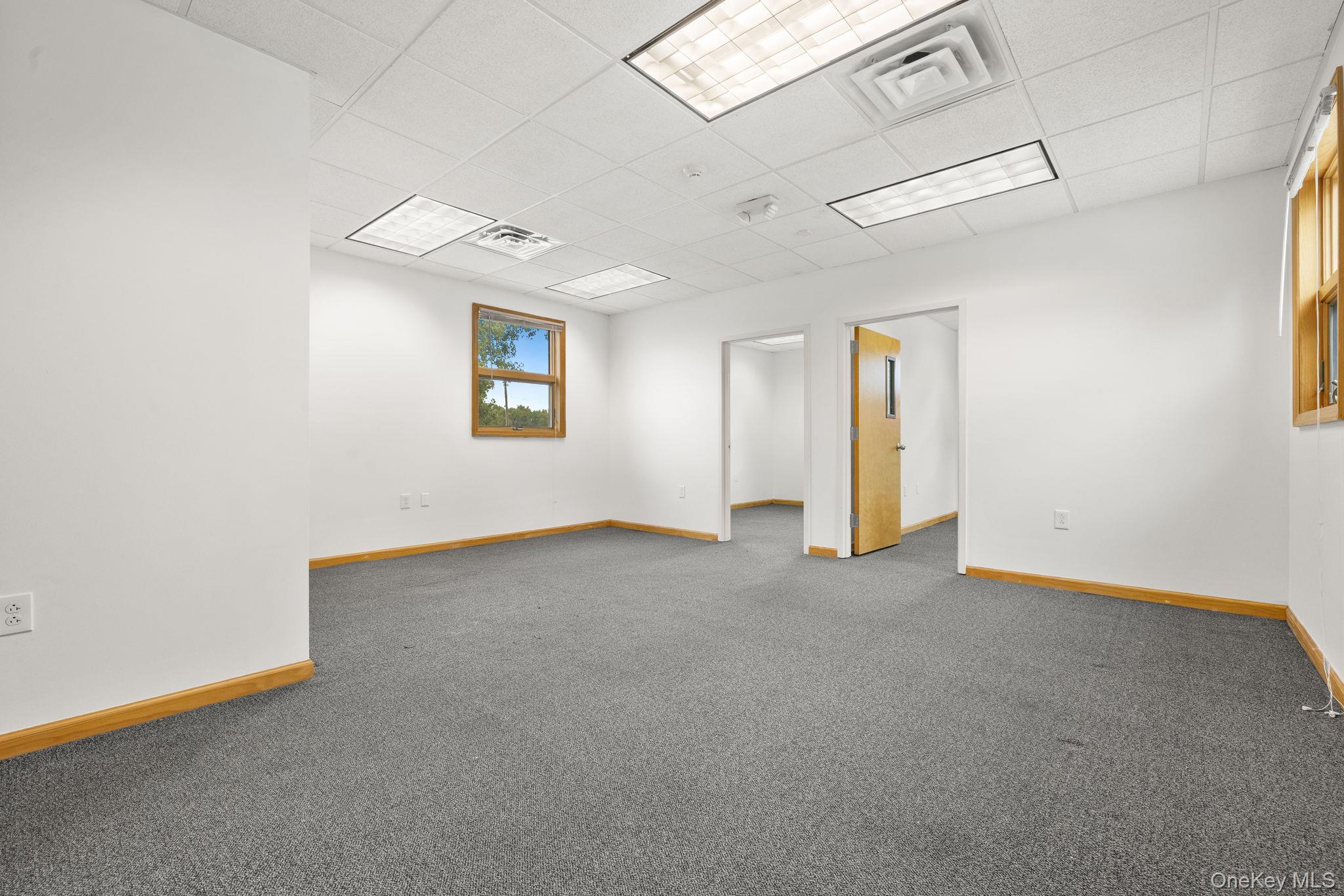 Carpeted empty room with a drop ceiling and baseboards