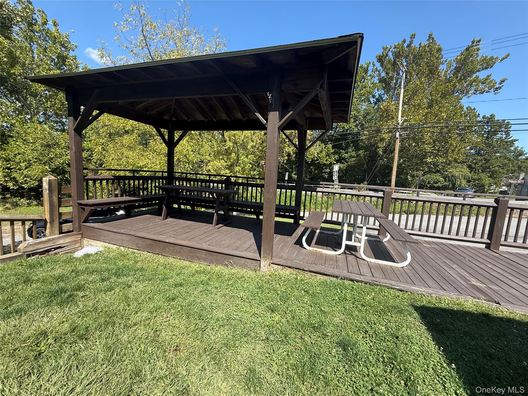 Deck with a lawn, view of wooded area, and a gazebo