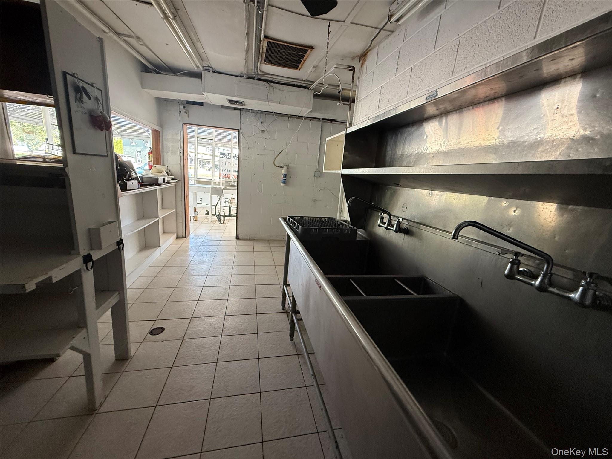 Kitchen with open shelves, light tile patterned floors, and concrete block wall