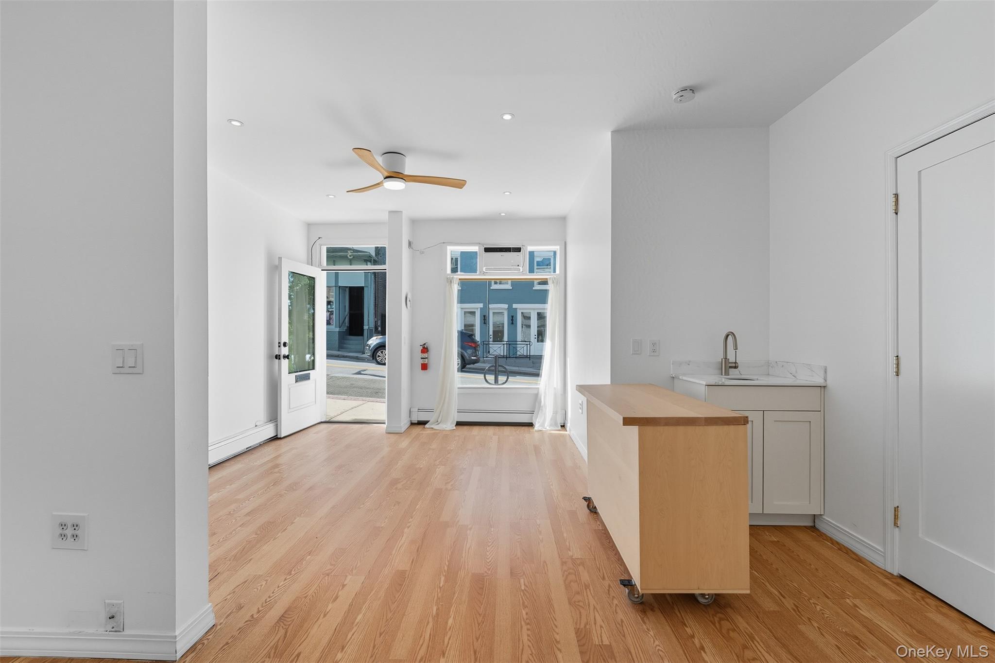 Bar with light wood-style flooring, wooden counters, and ceiling fan