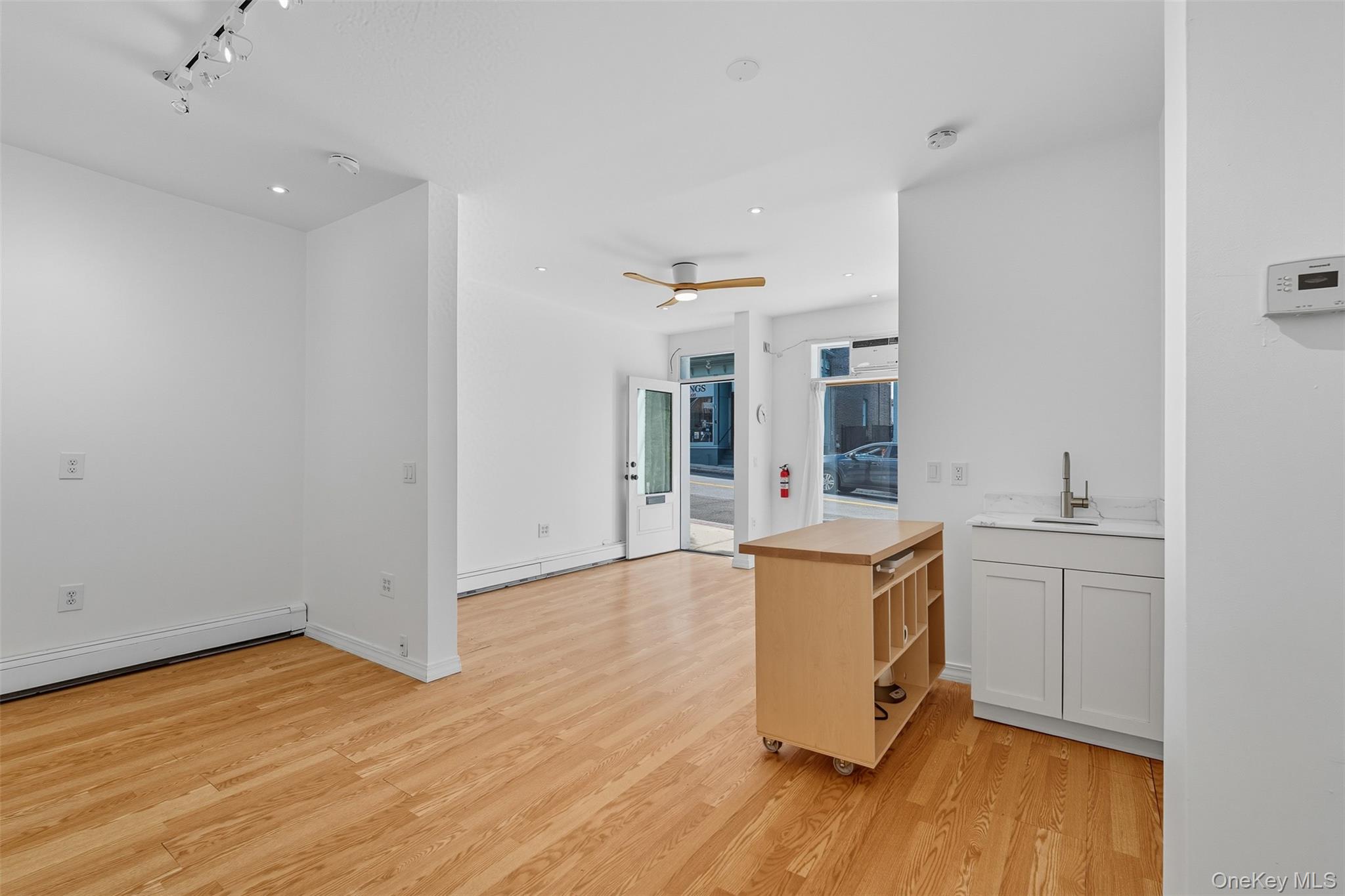 Kitchen with light wood-type flooring, a ceiling fan, butcher block countertops, open floor plan, and rail lighting