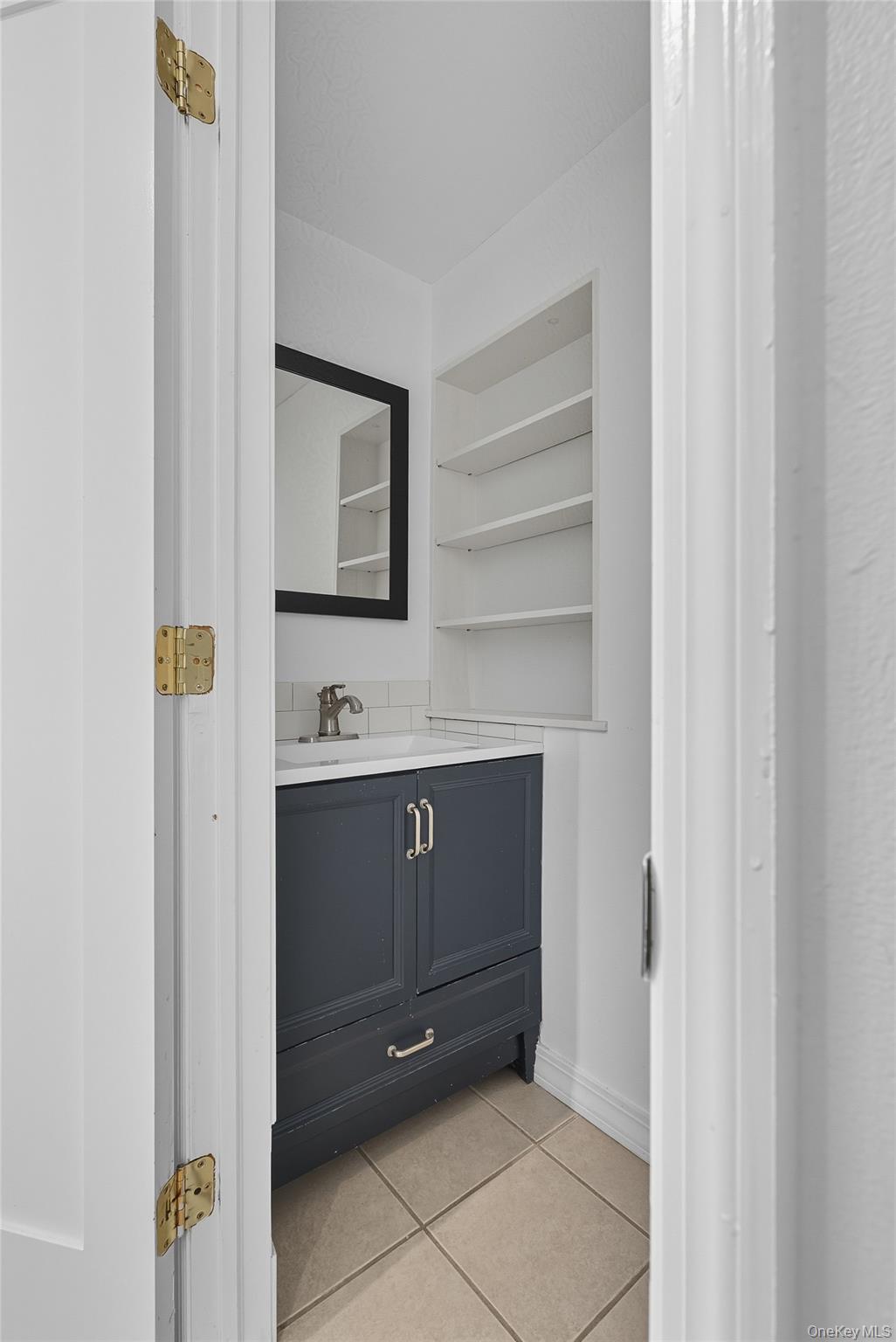 Bathroom with light tile patterned floors and vanity