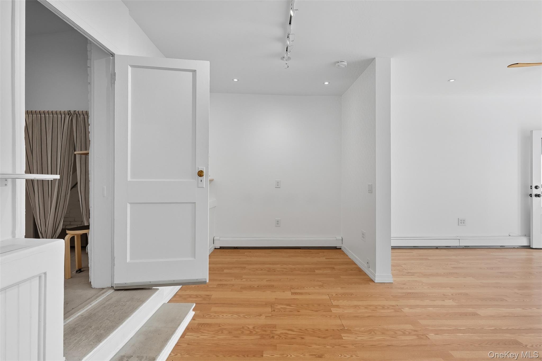Spare room with light wood-style floors, rail lighting, and a baseboard heating unit