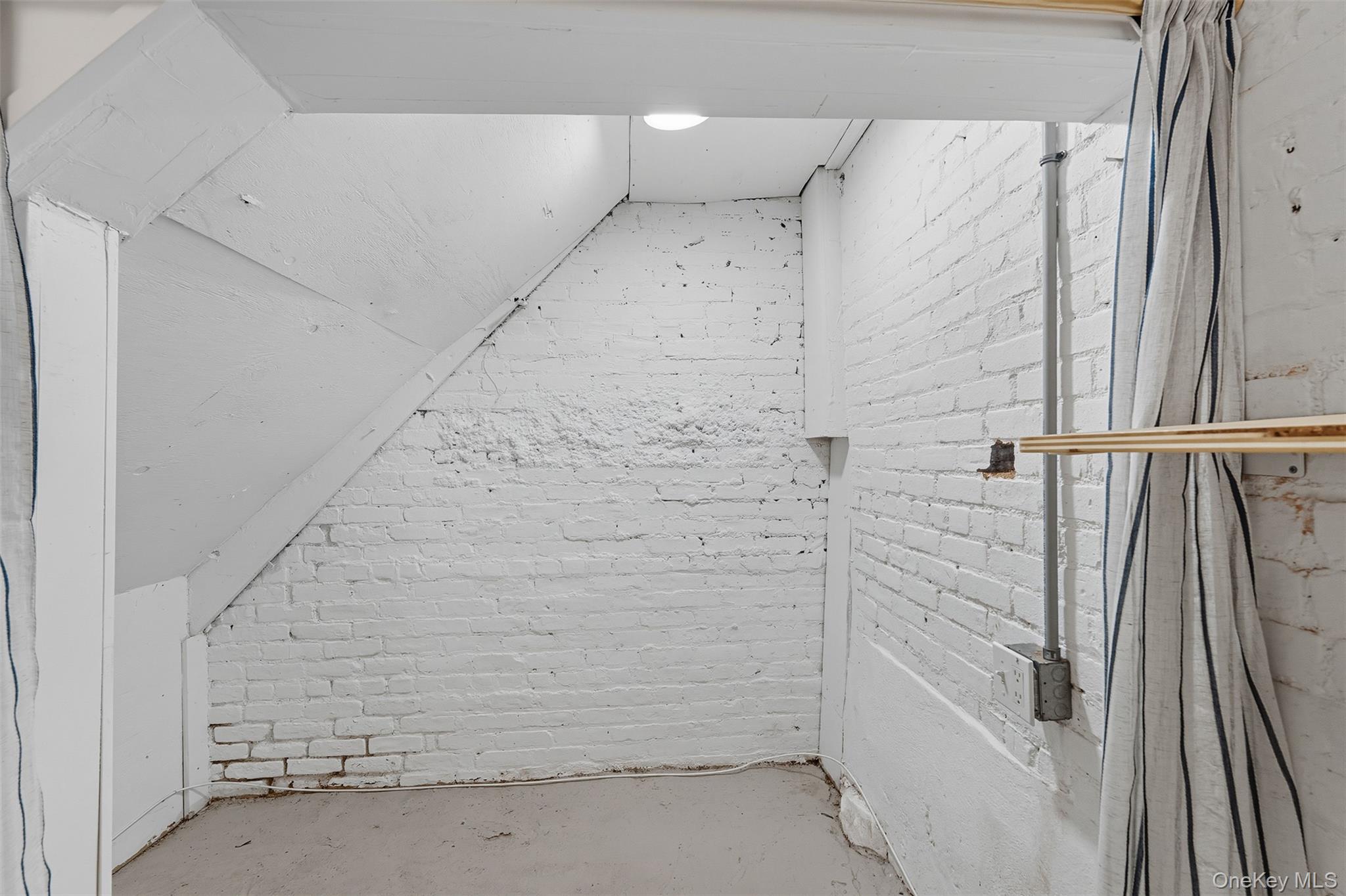 Bonus room with brick wall, concrete flooring, and vaulted ceiling